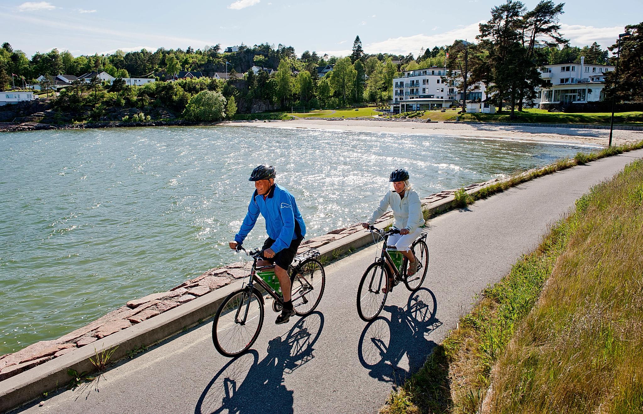 Un homme et une femme font du vélo au bord de la mer par une belle journée ensoleillée à Fevik, Grimstad, en Norvège du Sud