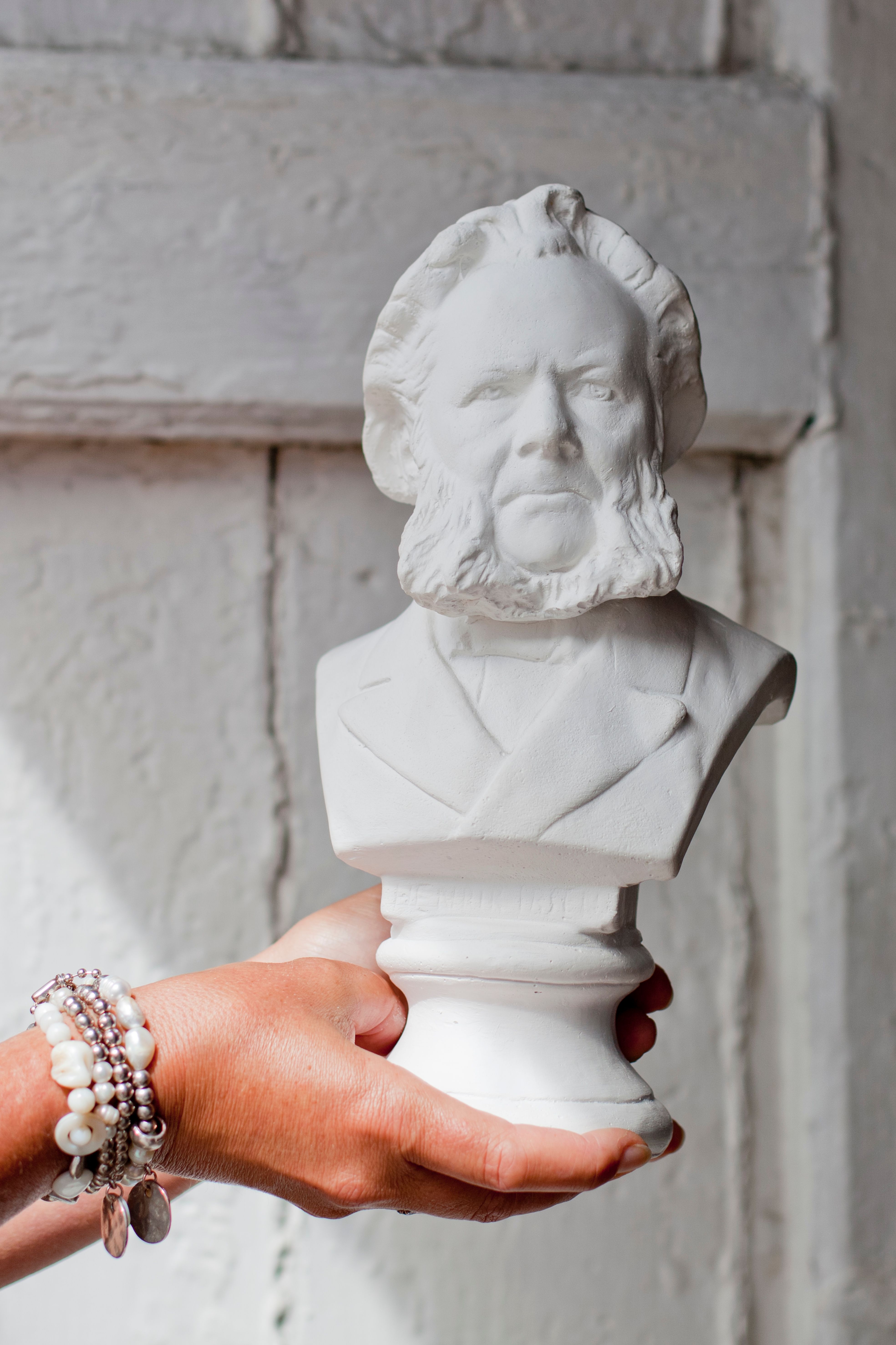 Hands holding up a white bust of Henrik Ibsen. Grimstad, Southern Norway.