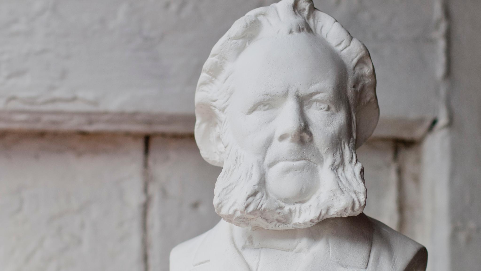 Hands holding up a white bust of Henrik Ibsen. Grimstad, Southern Norway.