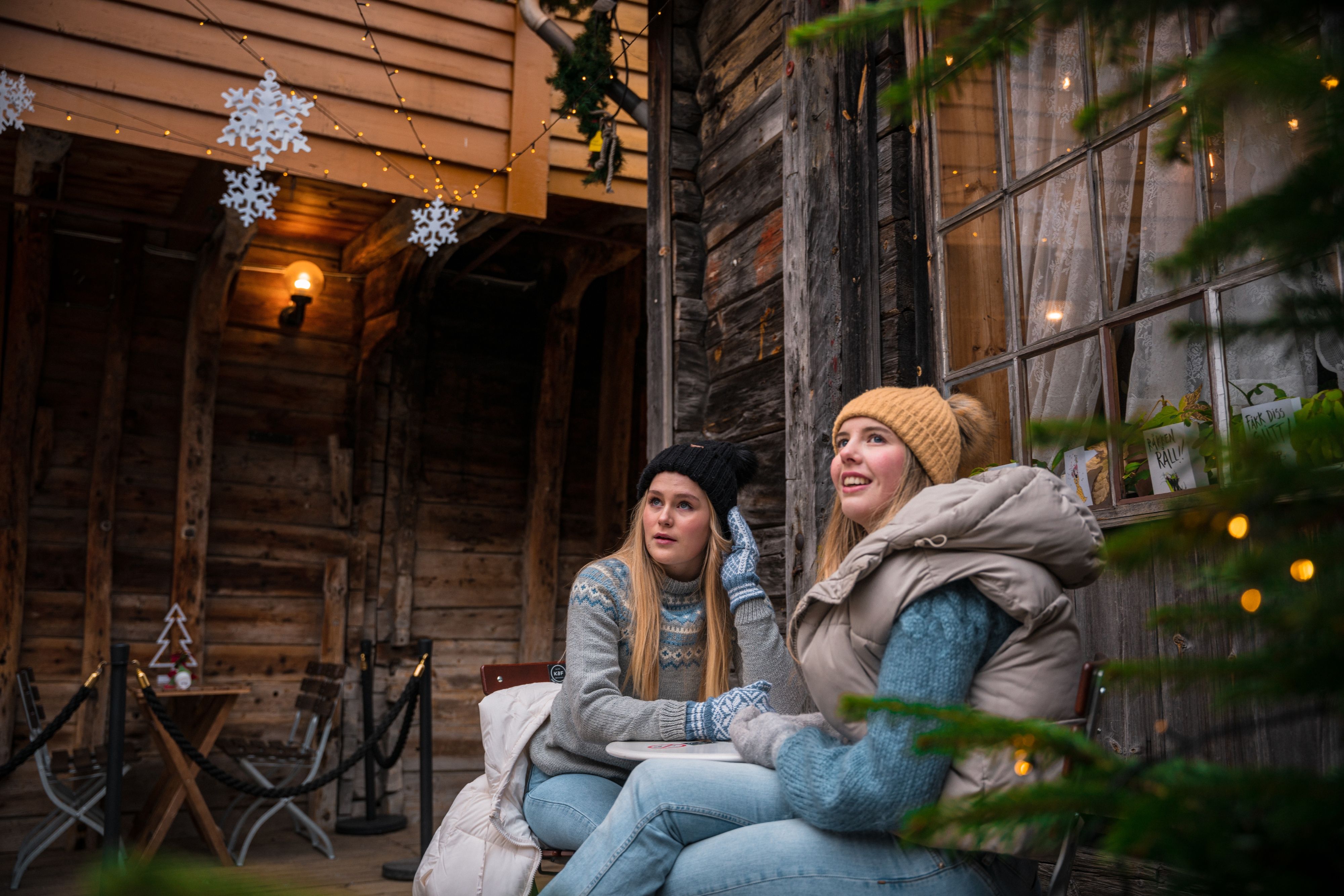 Two girls sitting at the Christmas decorated wharf in Bergen, Fjord Norway