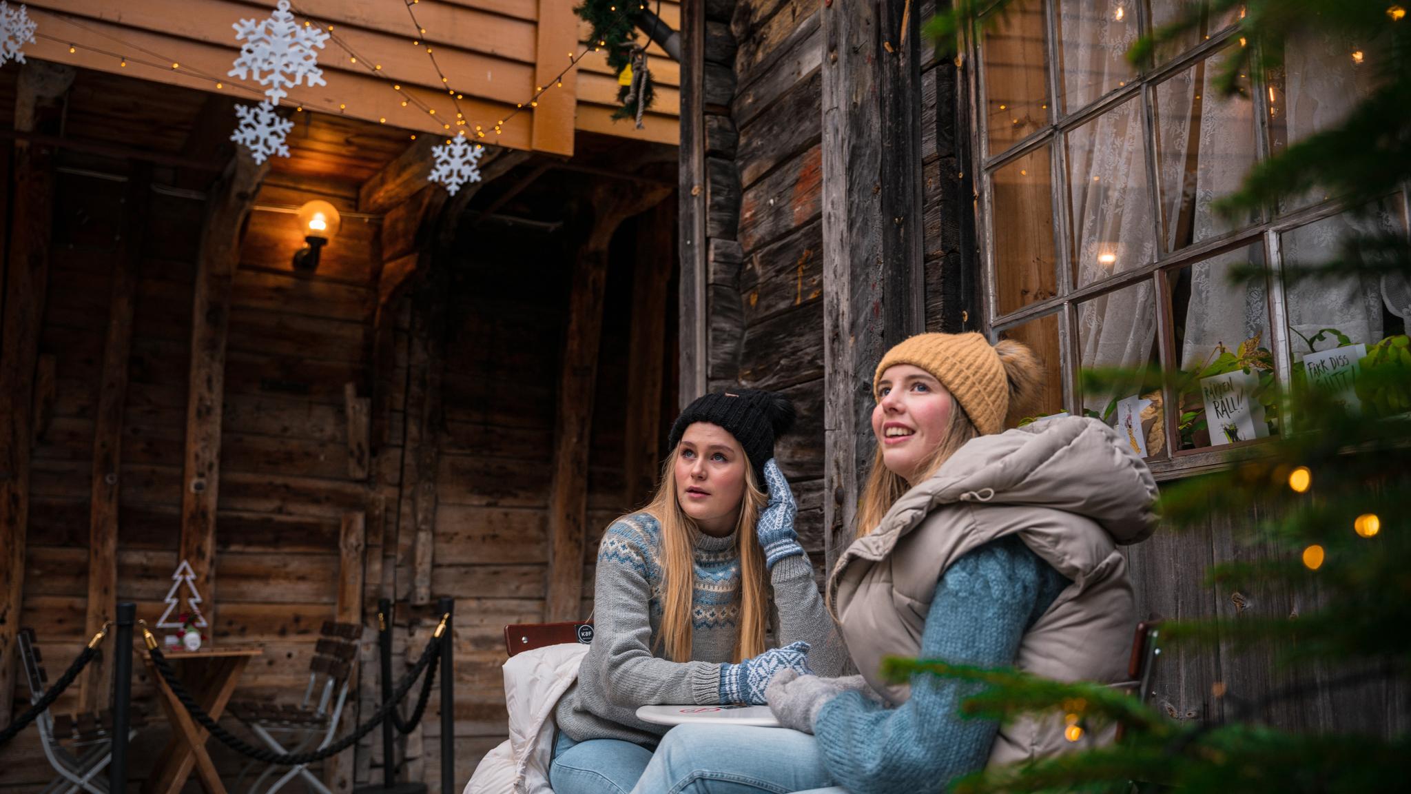 Two girls sitting at the Christmas decorated wharf in Bergen, Fjord Norway