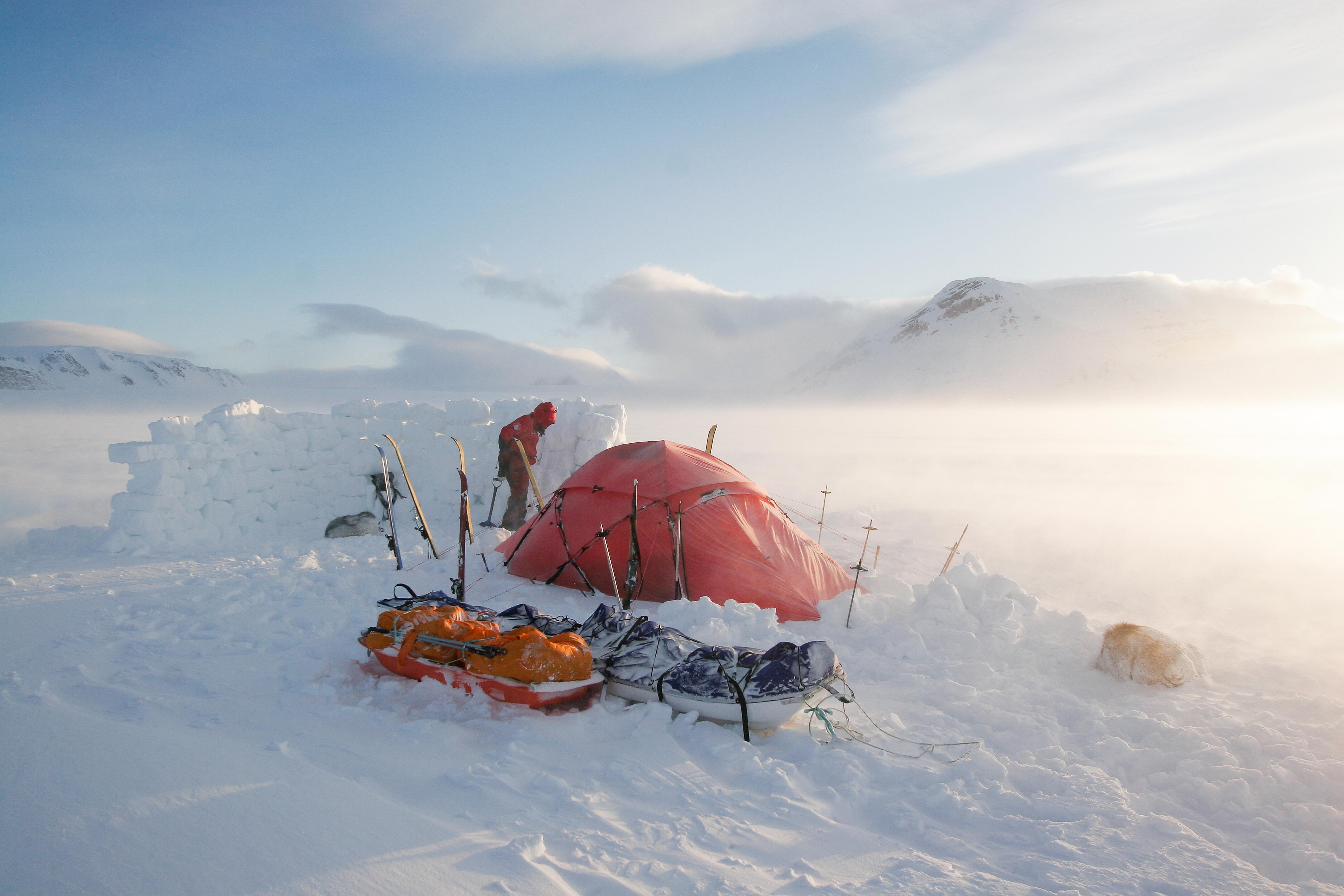 A red tent, several skis in the snow and two sledges in a snow-clad landscape in Longyearbyen on Svalbard in Northern Norway