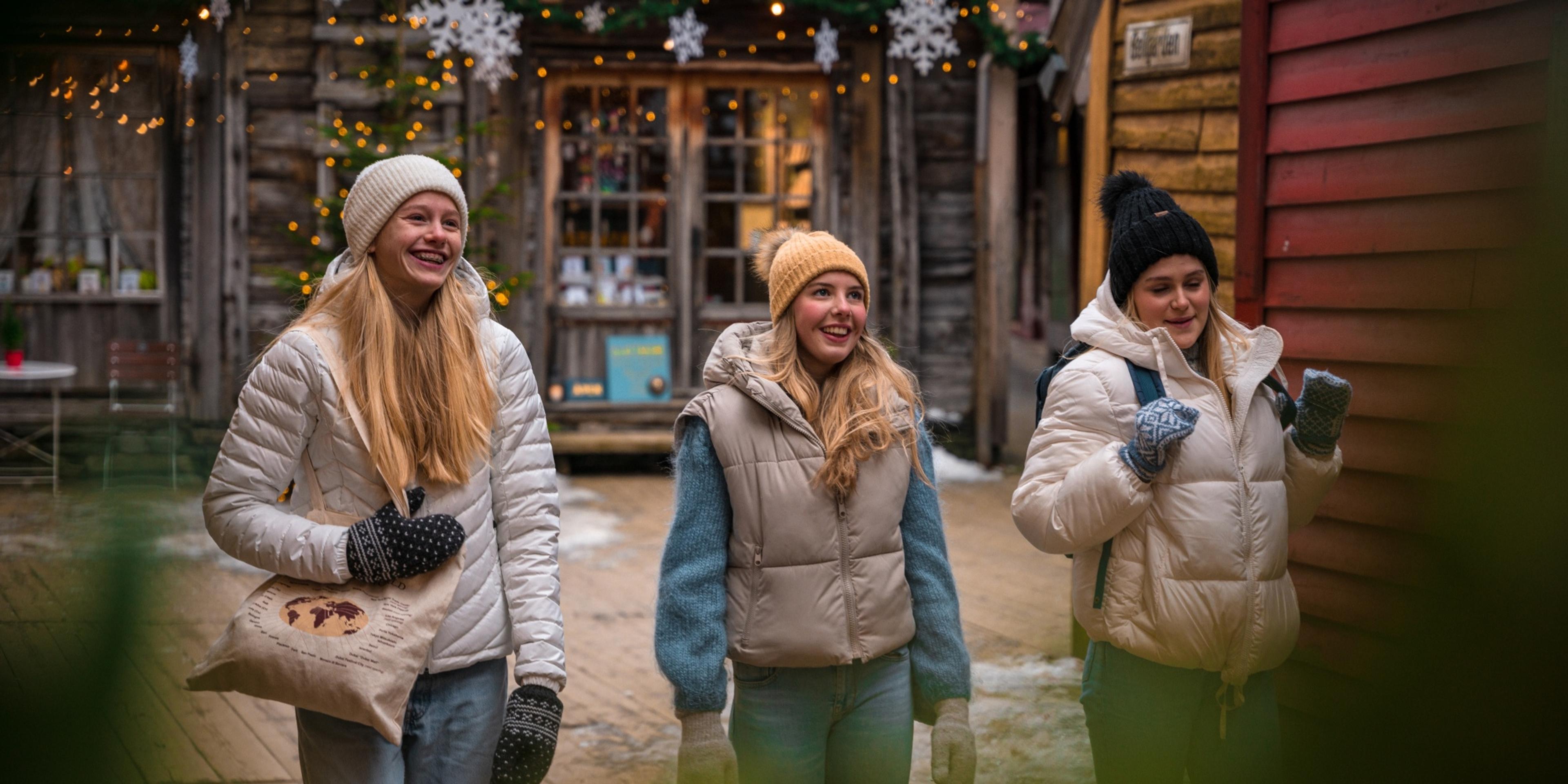 Three girls walking between the Christmassy wooden houses in Bergen, Fjord Norway