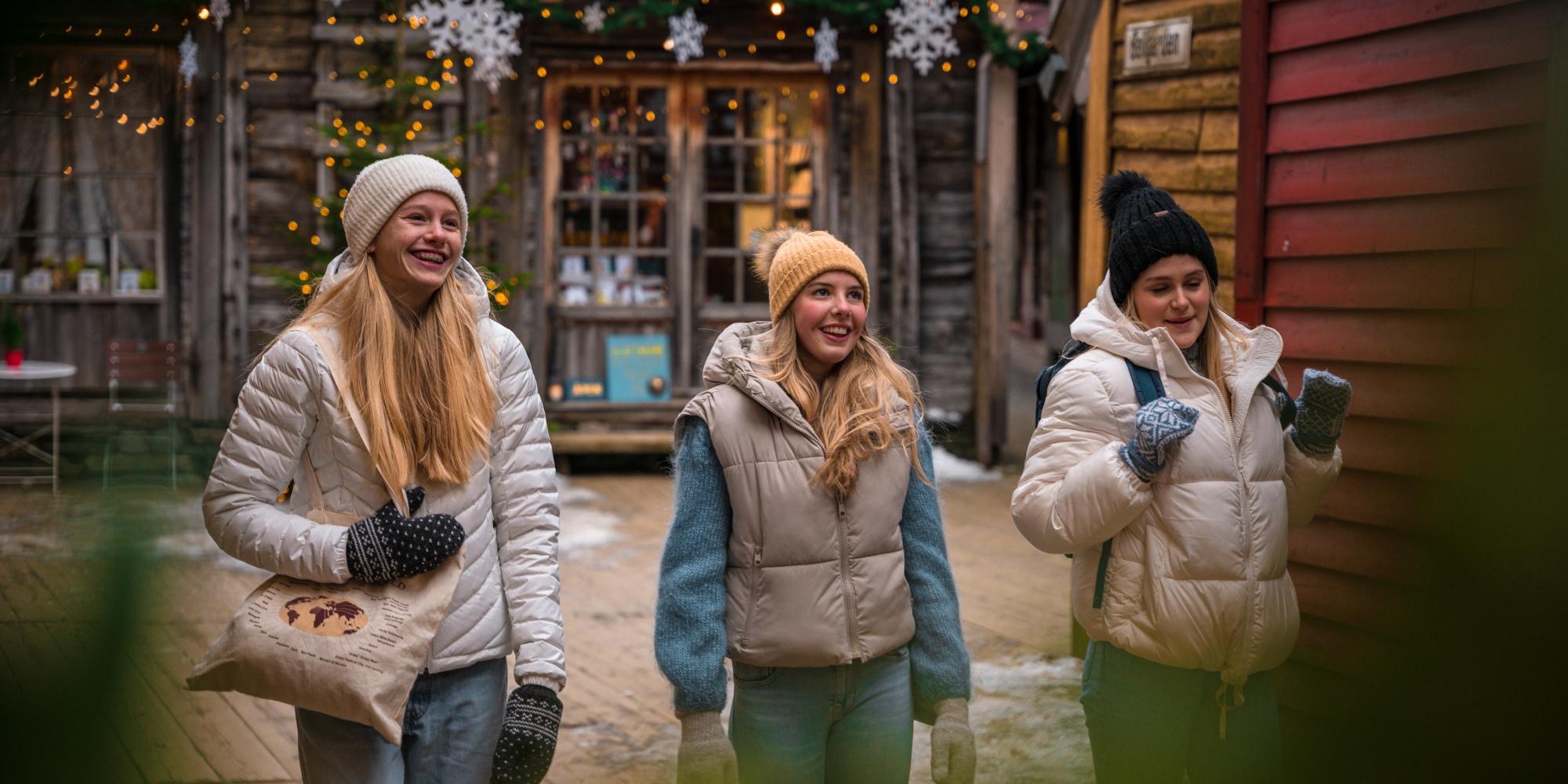 Three girls walking between the Christmassy wooden houses in Bergen, Fjord Norway