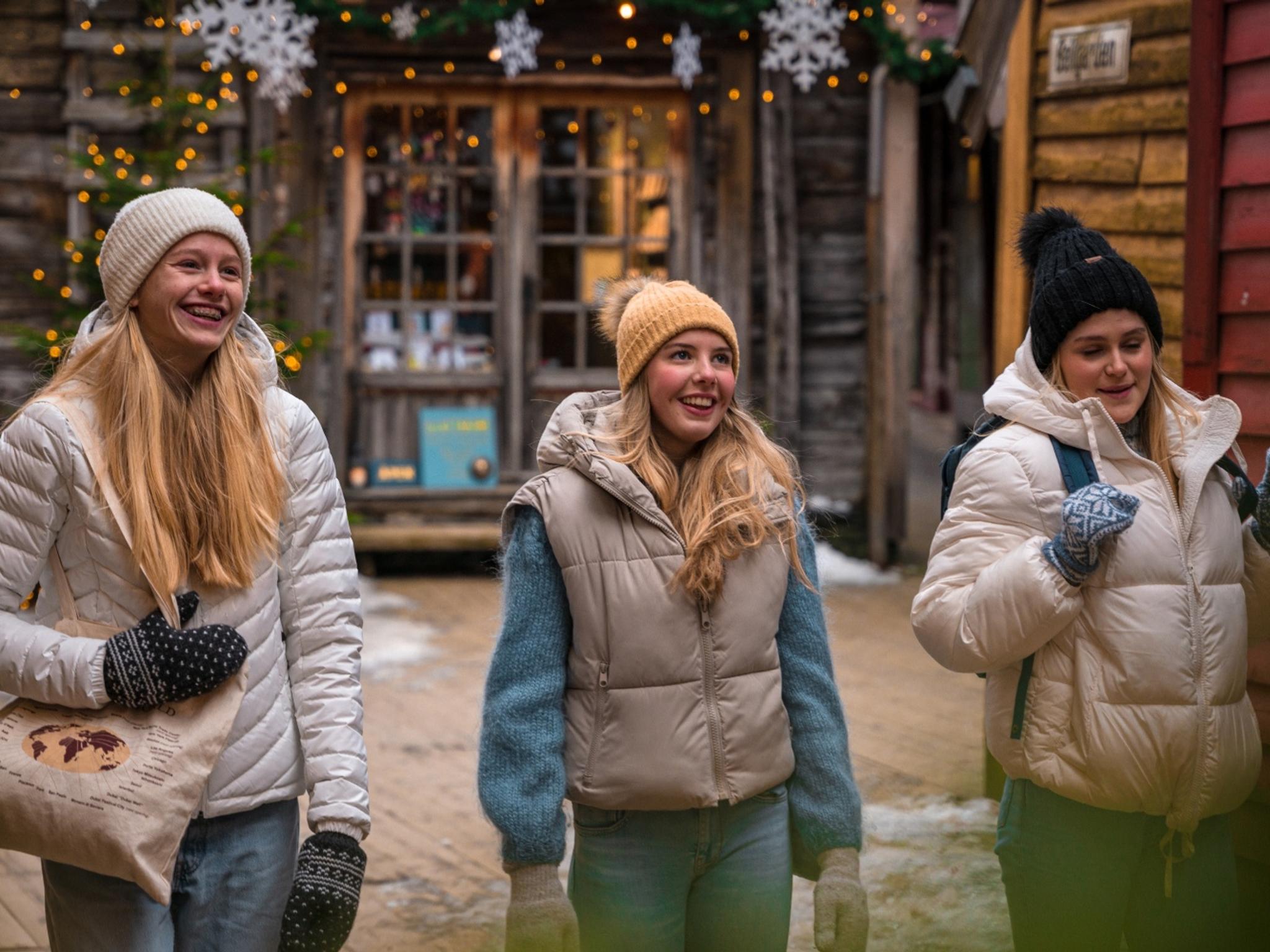 Three girls walking between the Christmassy wooden houses in Bergen, Fjord Norway