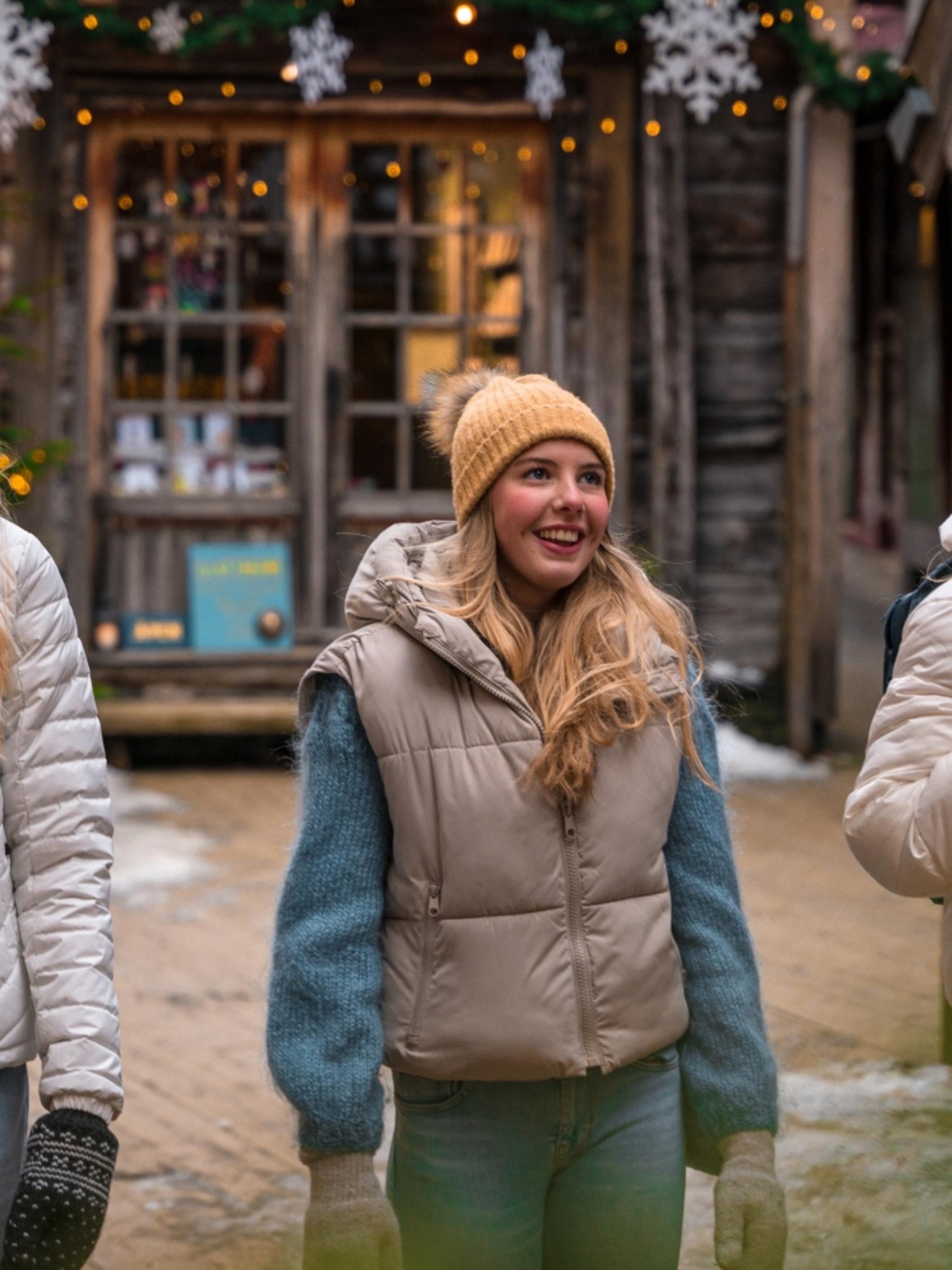 Three girls walking between the Christmassy wooden houses in Bergen, Fjord Norway