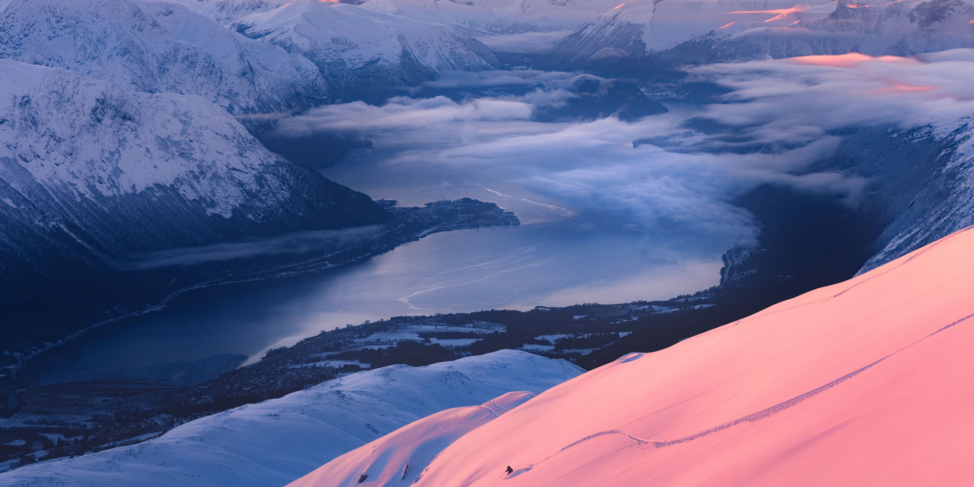 A person skiing down slopes during the sunset