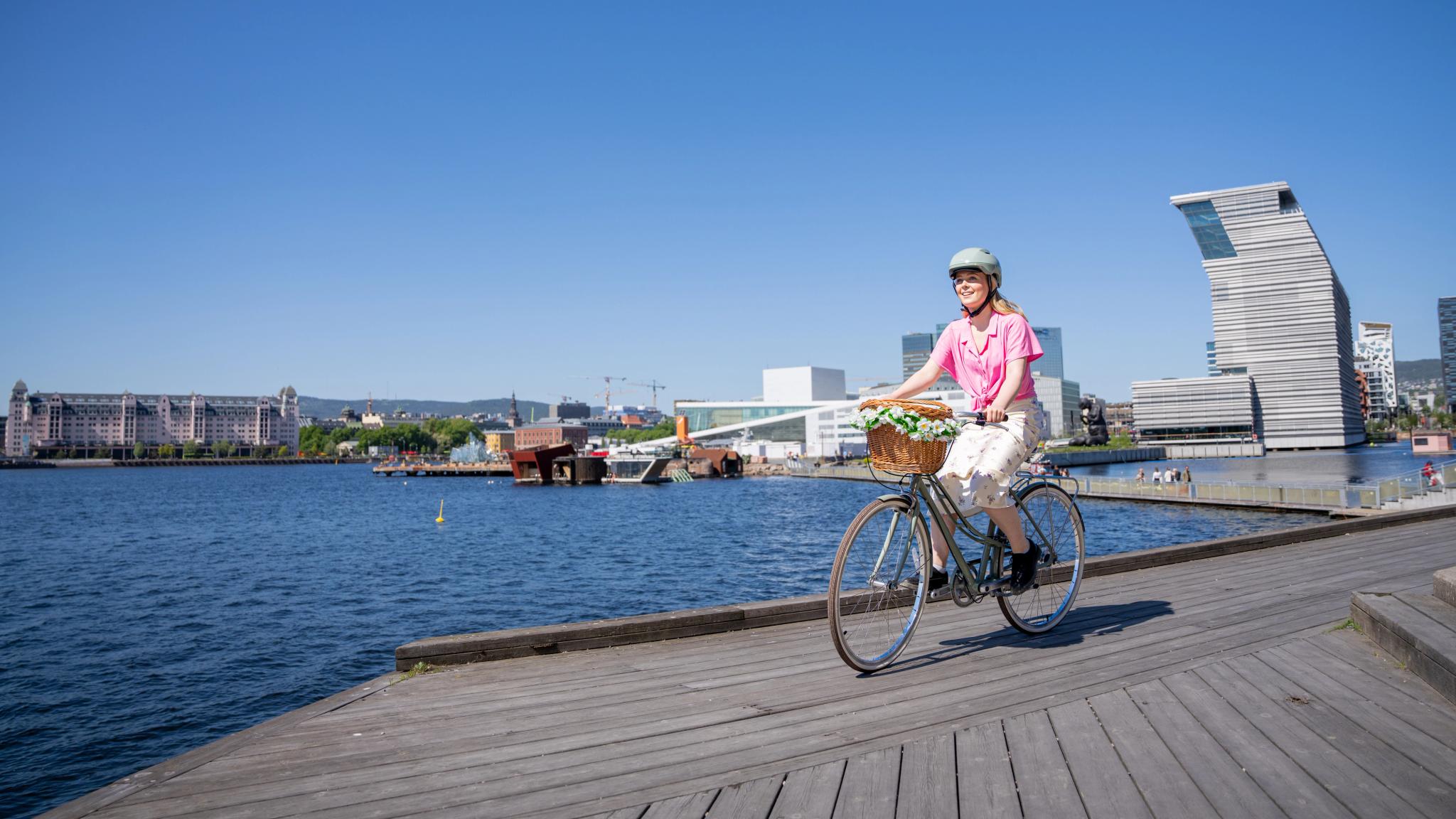 A girl cycling along the harbour in Oslo