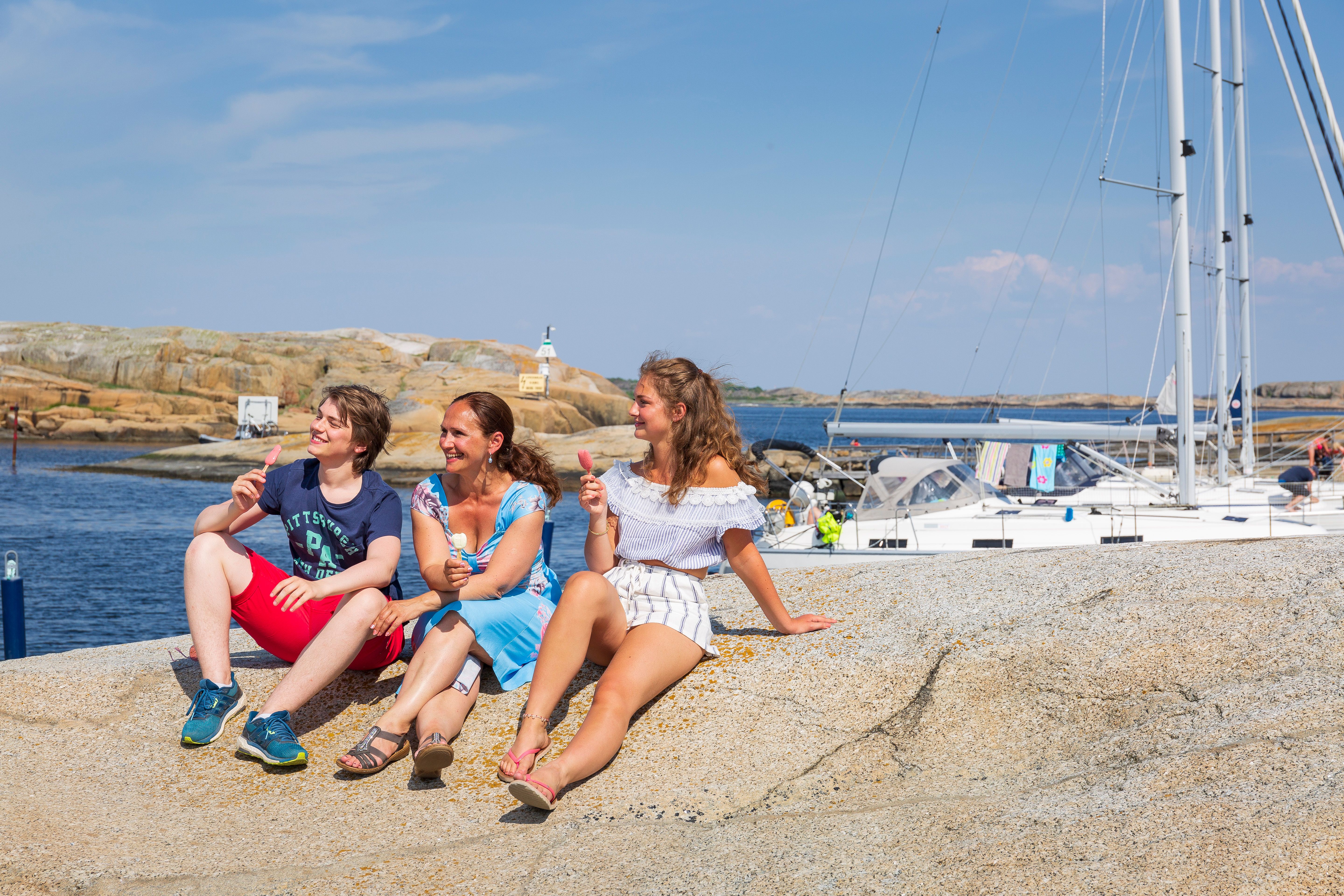 Three people sitting on an islet at Verdens Ende at the southern tip of Tjøme island in Vestfold, Eastern Norway