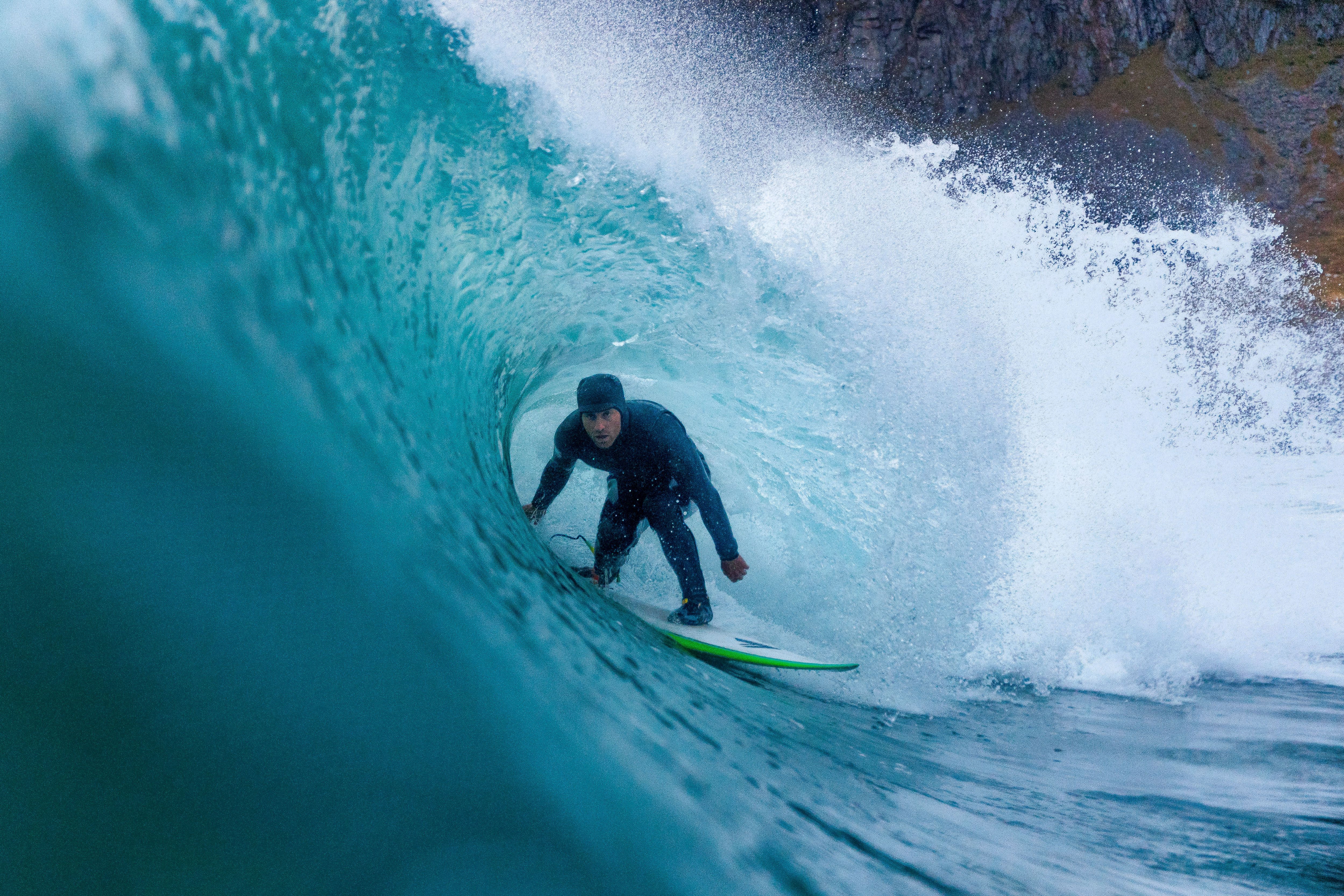 A surfer riding under a breaking wave on Lofoten islands in Northern Norway