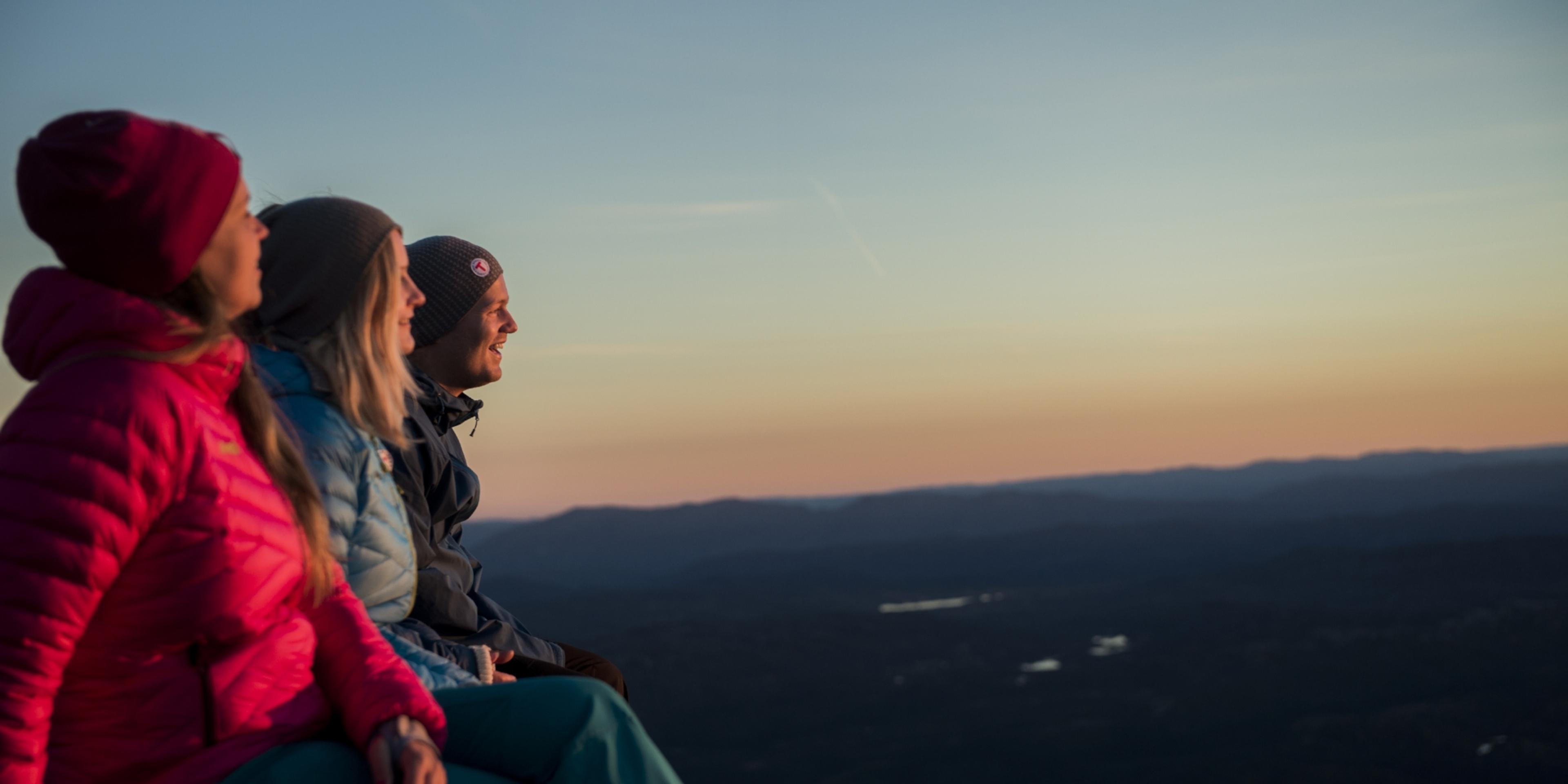 Tre personer nyder udsigten fra Gaustatoppen, Telemark i Norge