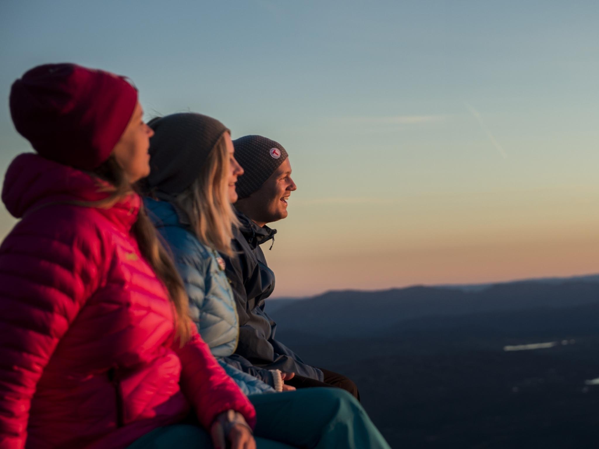 Tre personer tar in utsikten från Gaustatoppen i Telemark, östra Norge
