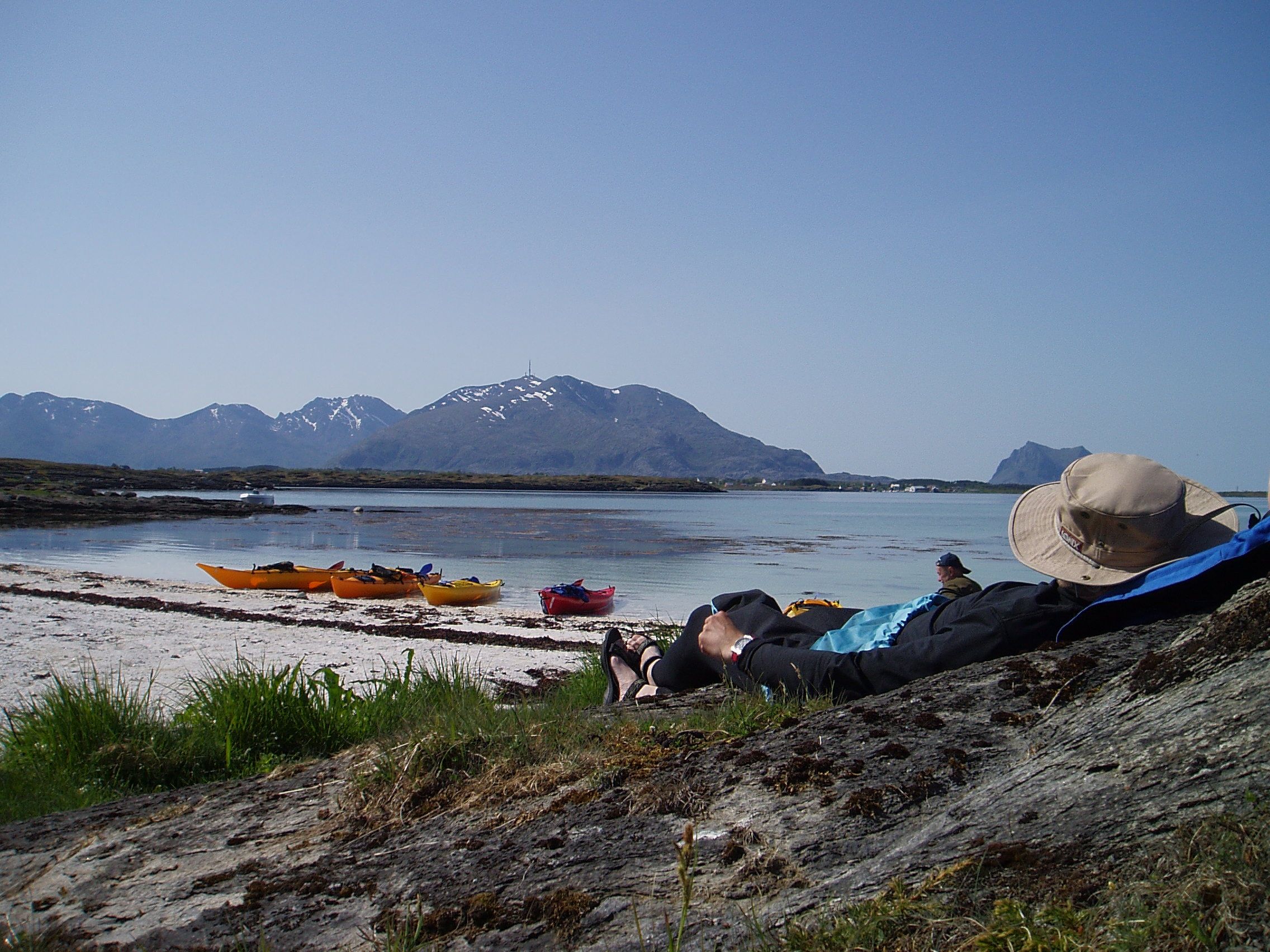 A person is relaxing by the beach on a kayaking trip in the Vega islands outside the Helgeland coast in Northern Norway
