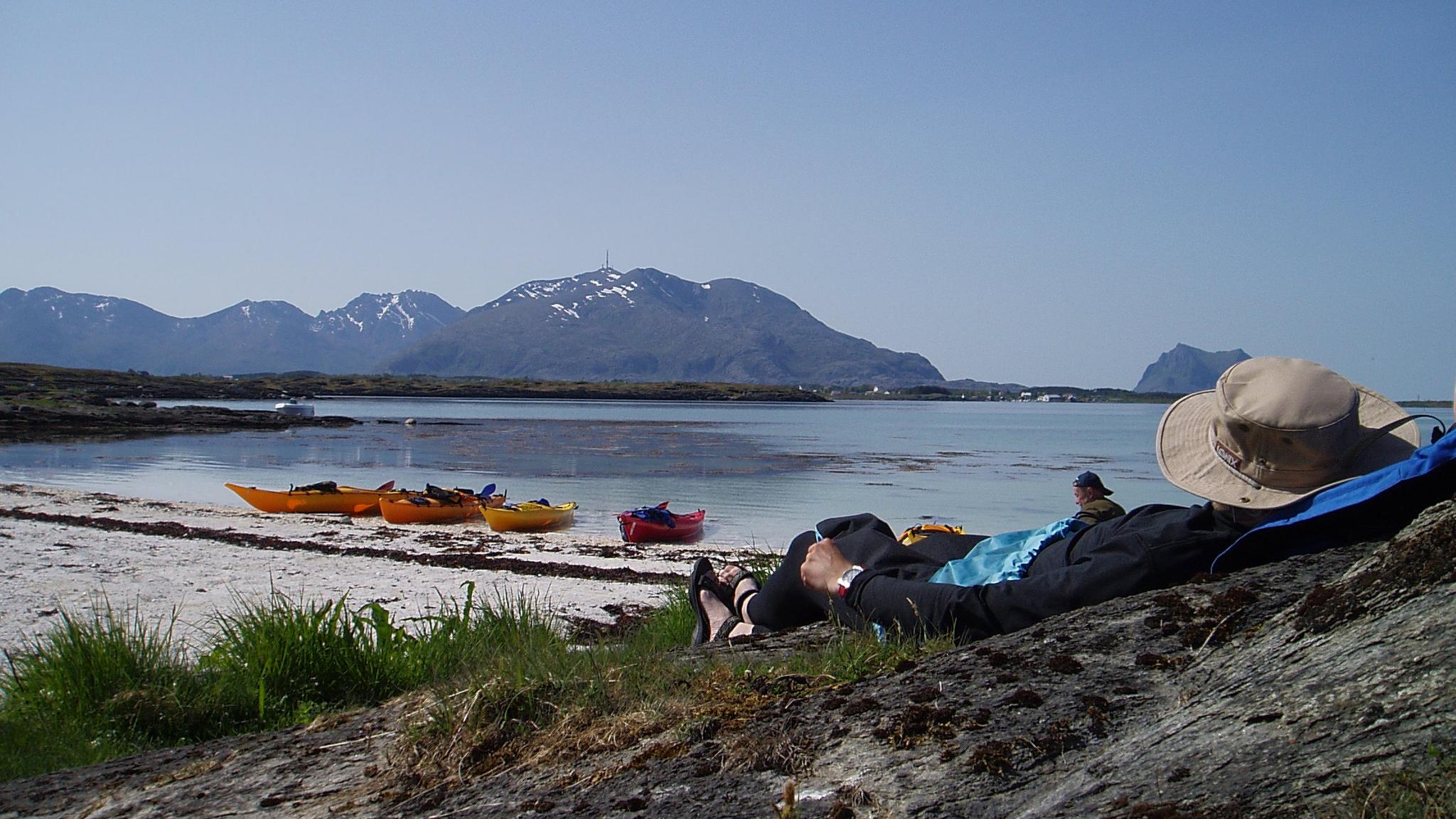A person is relaxing by the beach on a kayaking trip in the Vega islands outside the Helgeland coast in Northern Norway