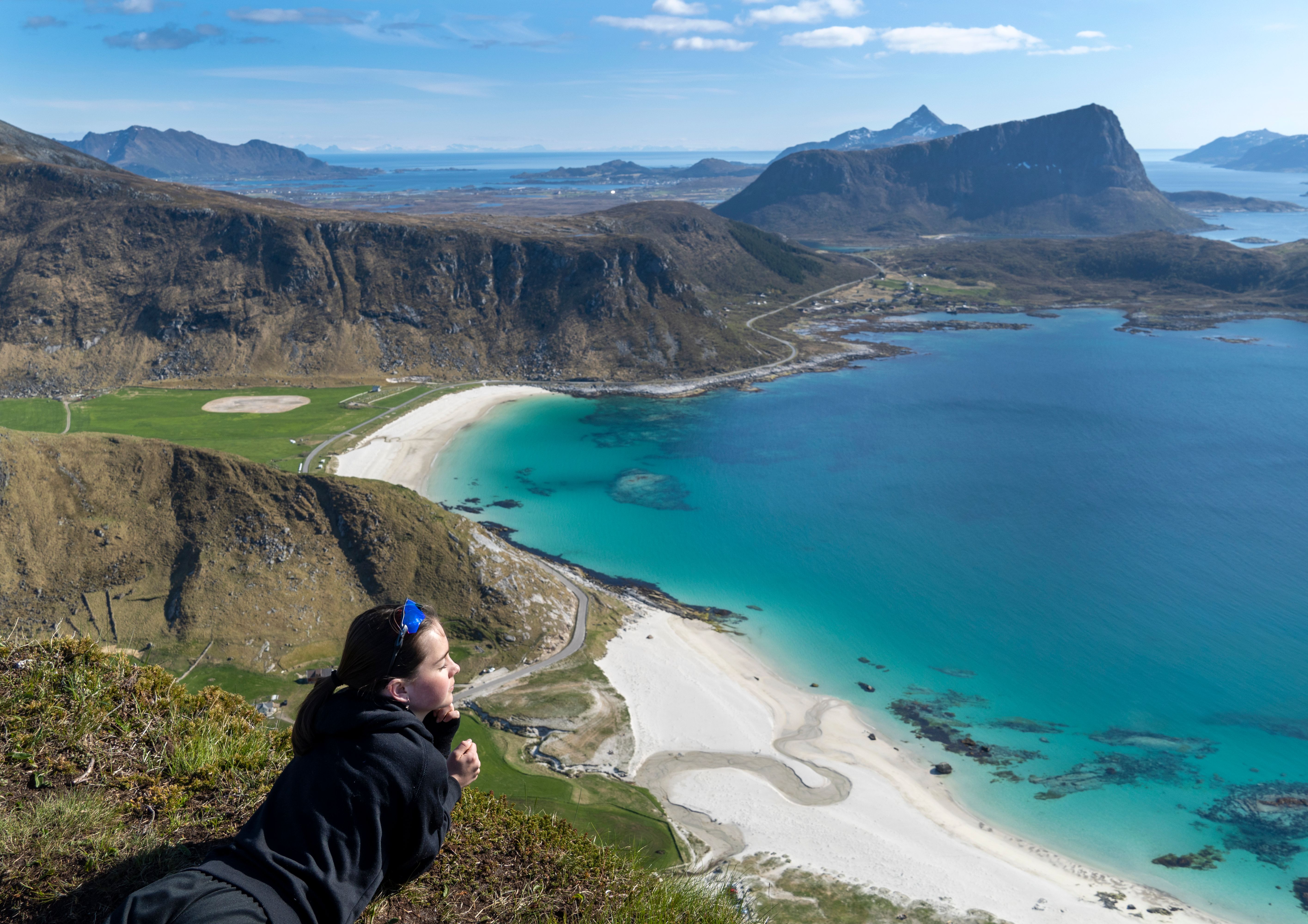 Girl enjoying the view from a mountain by Hauklandstranda beach in Lofoten in Northern Norway