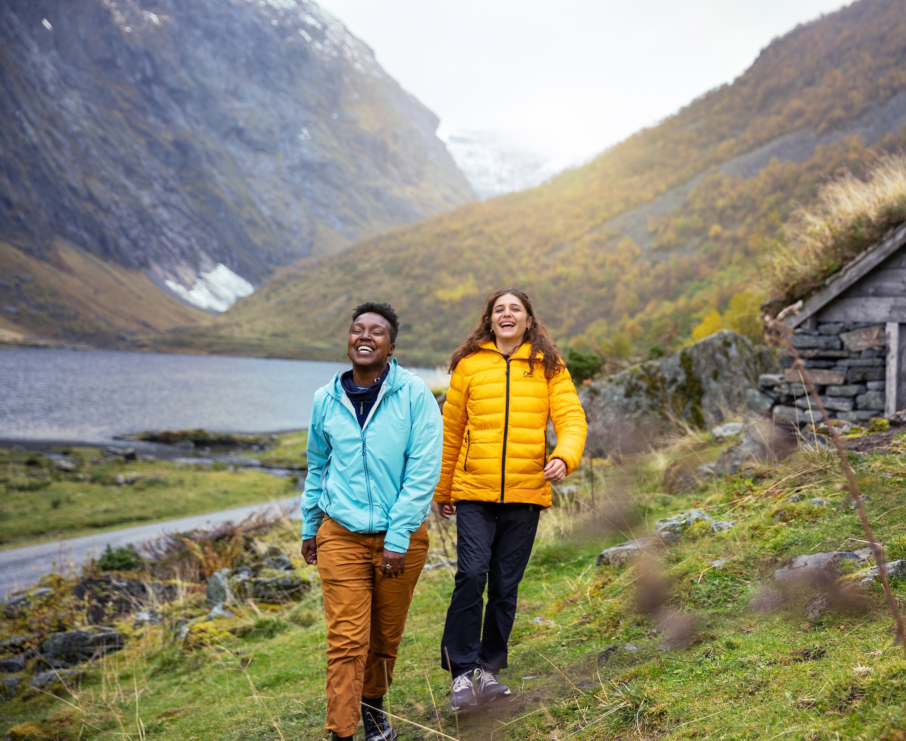 Two women hiking by the Hjørundfjord in Fjord Norway in autumn