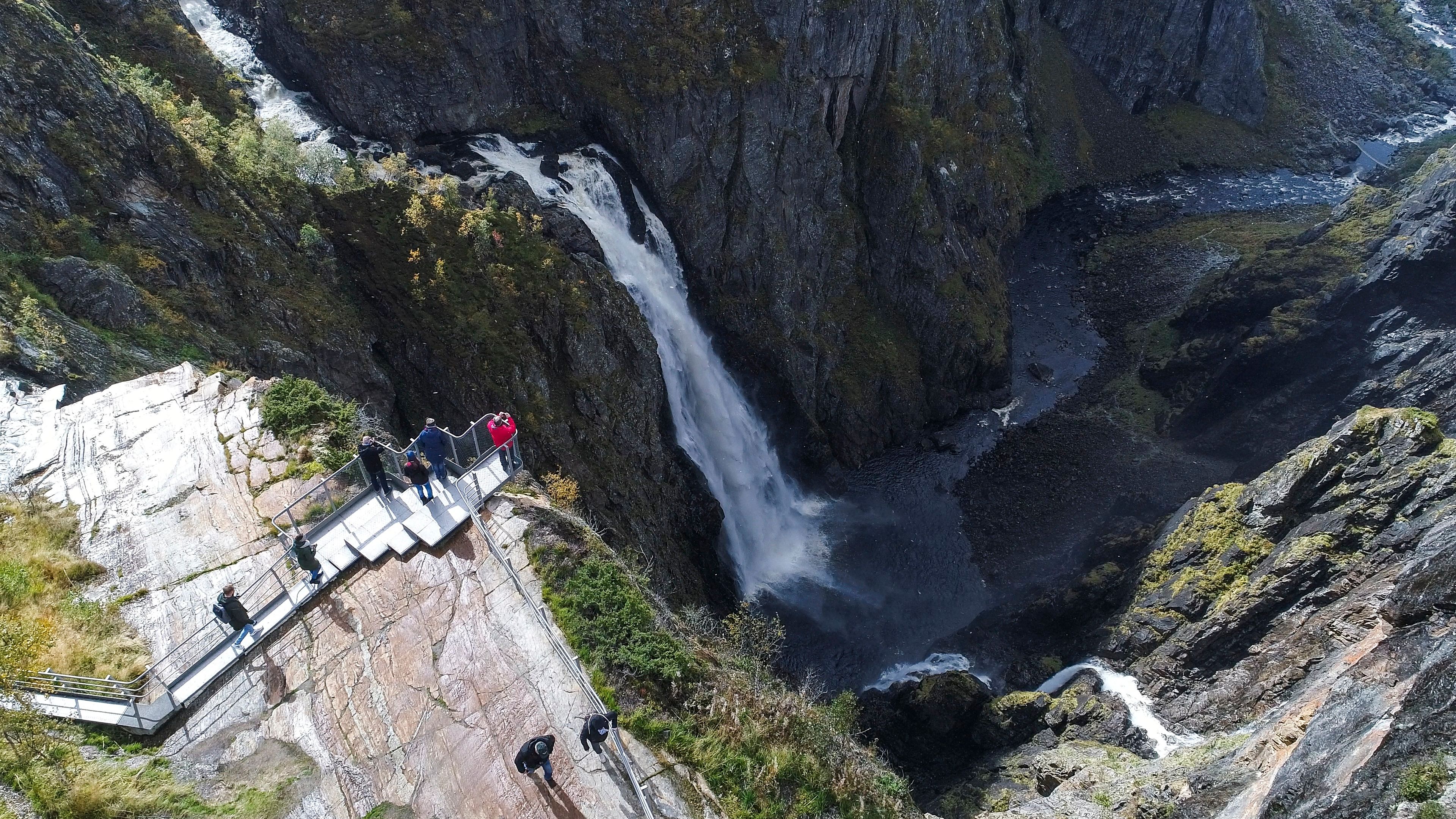 People standing on the Vøringsfossen viewpoint overlooking the waterfall. Norwegian Scenic Route Hardangervidda, Fjord Norway