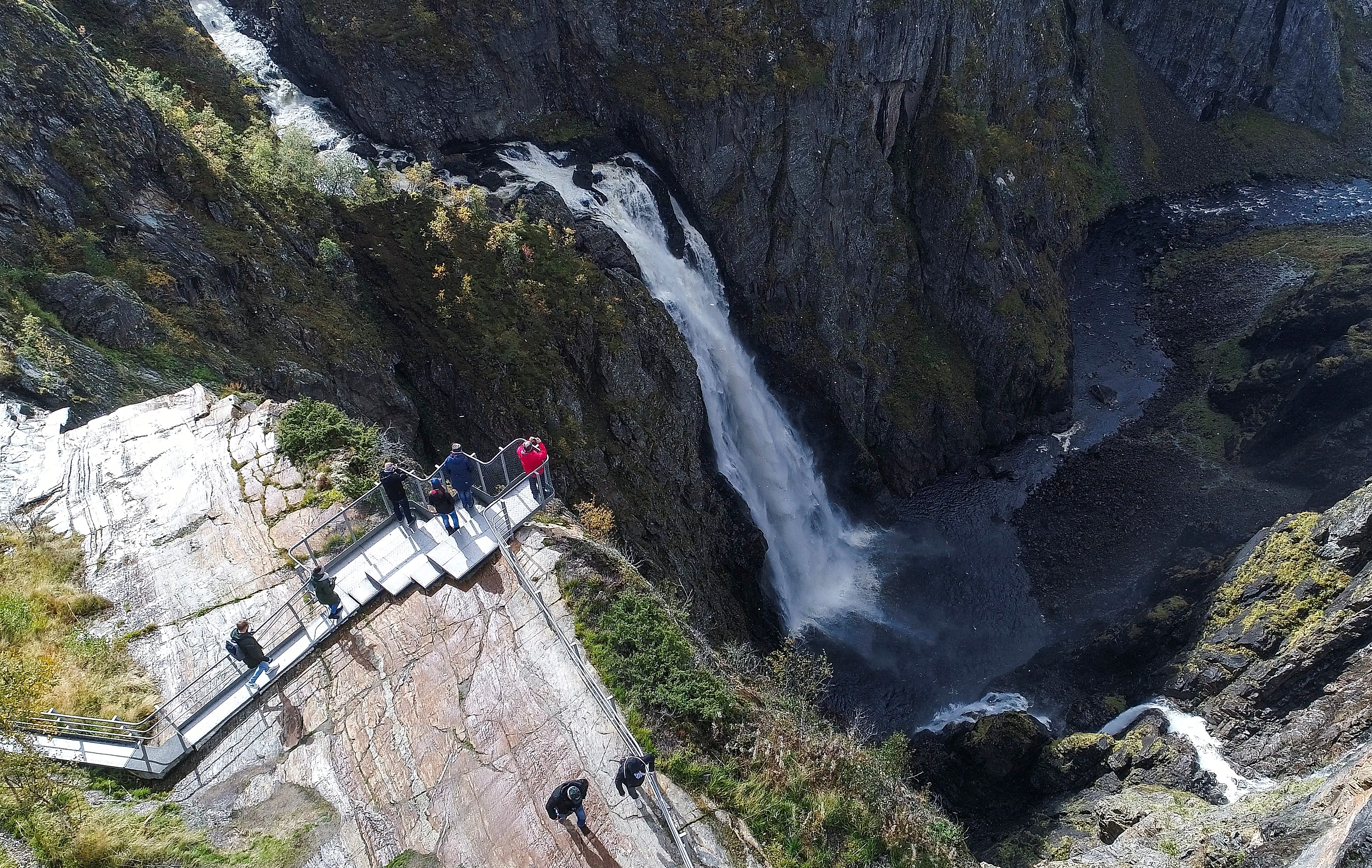 People standing on the Vøringsfossen viewpoint overlooking the waterfall. Norwegian Scenic Route Hardangervidda, Fjord Norway