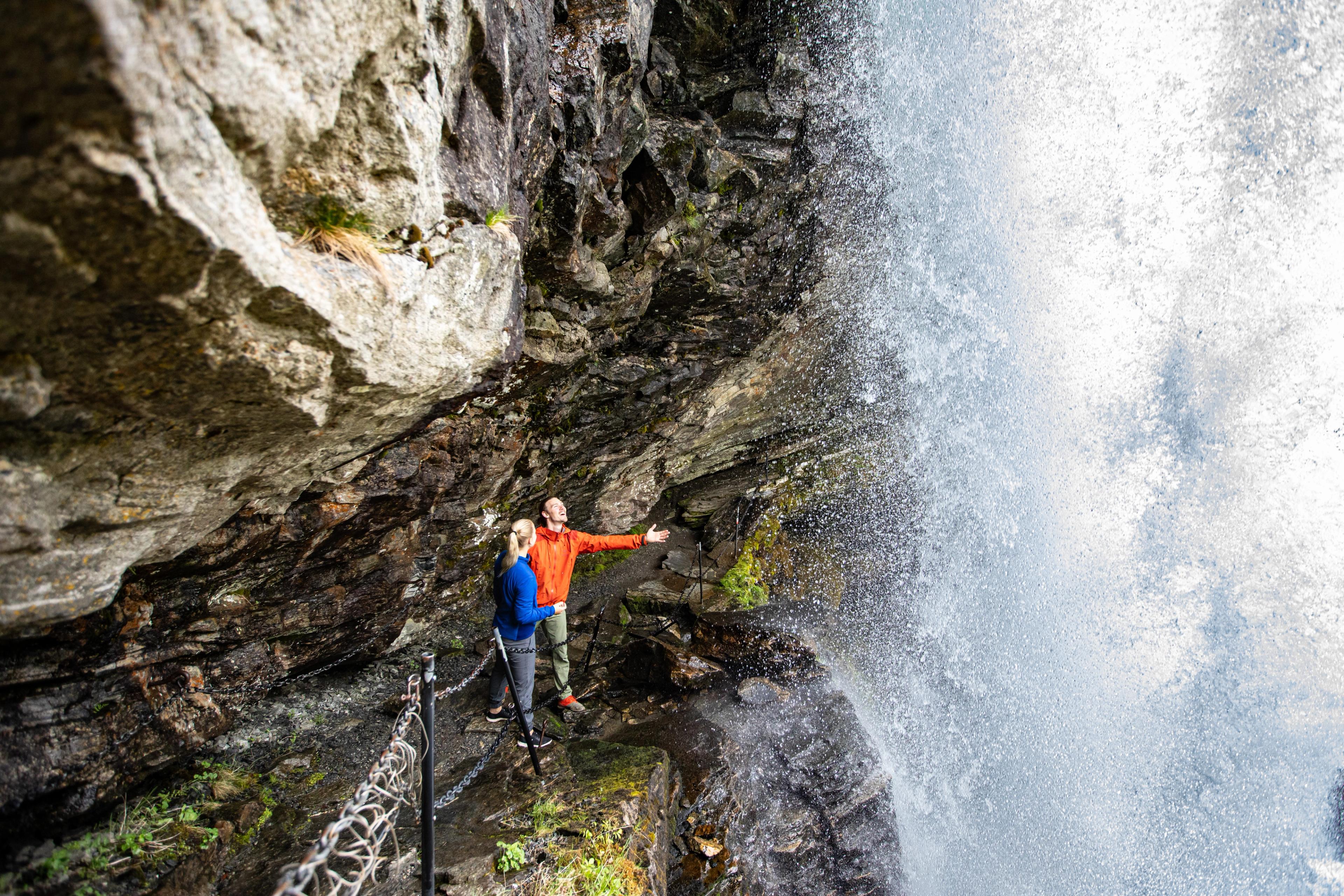 Couple hiking under the Fosseråsa in Geiranger, Fjord Norway