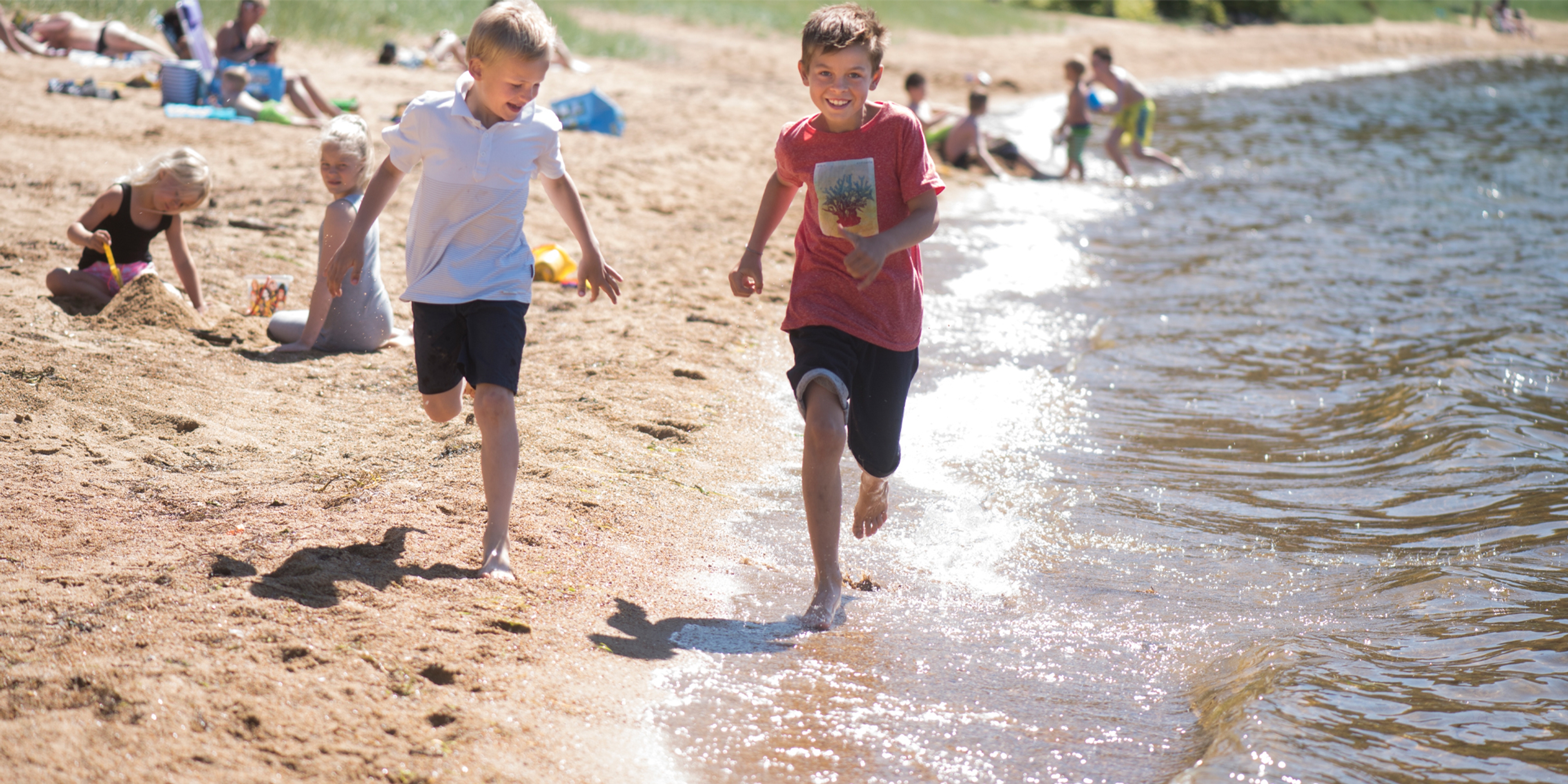 Two children running by the waterline on Kvavik beach in Lyngdal, Southern Norway