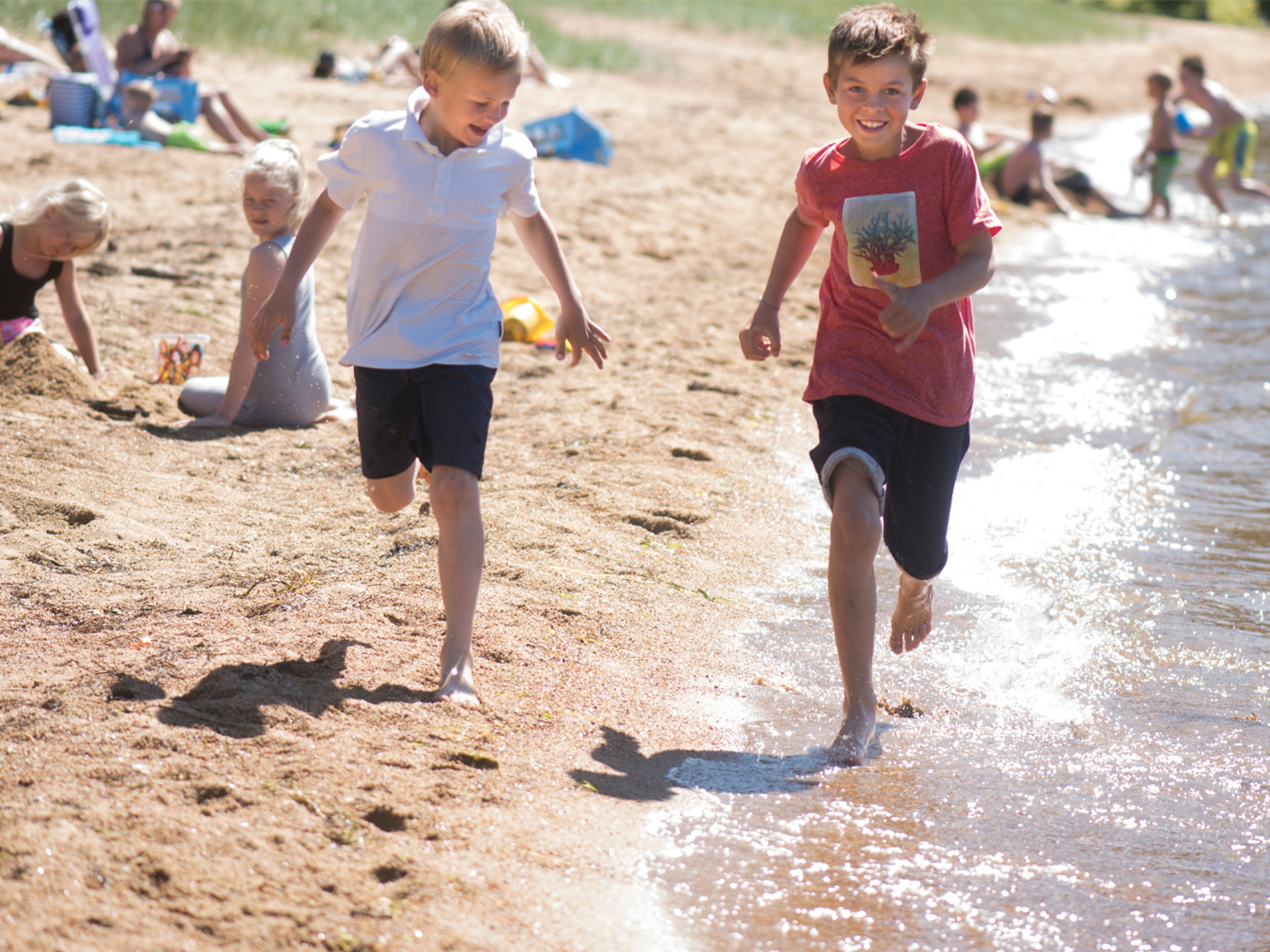 Two children running by the waterline on Kvavik beach in Lyngdal, Southern Norway