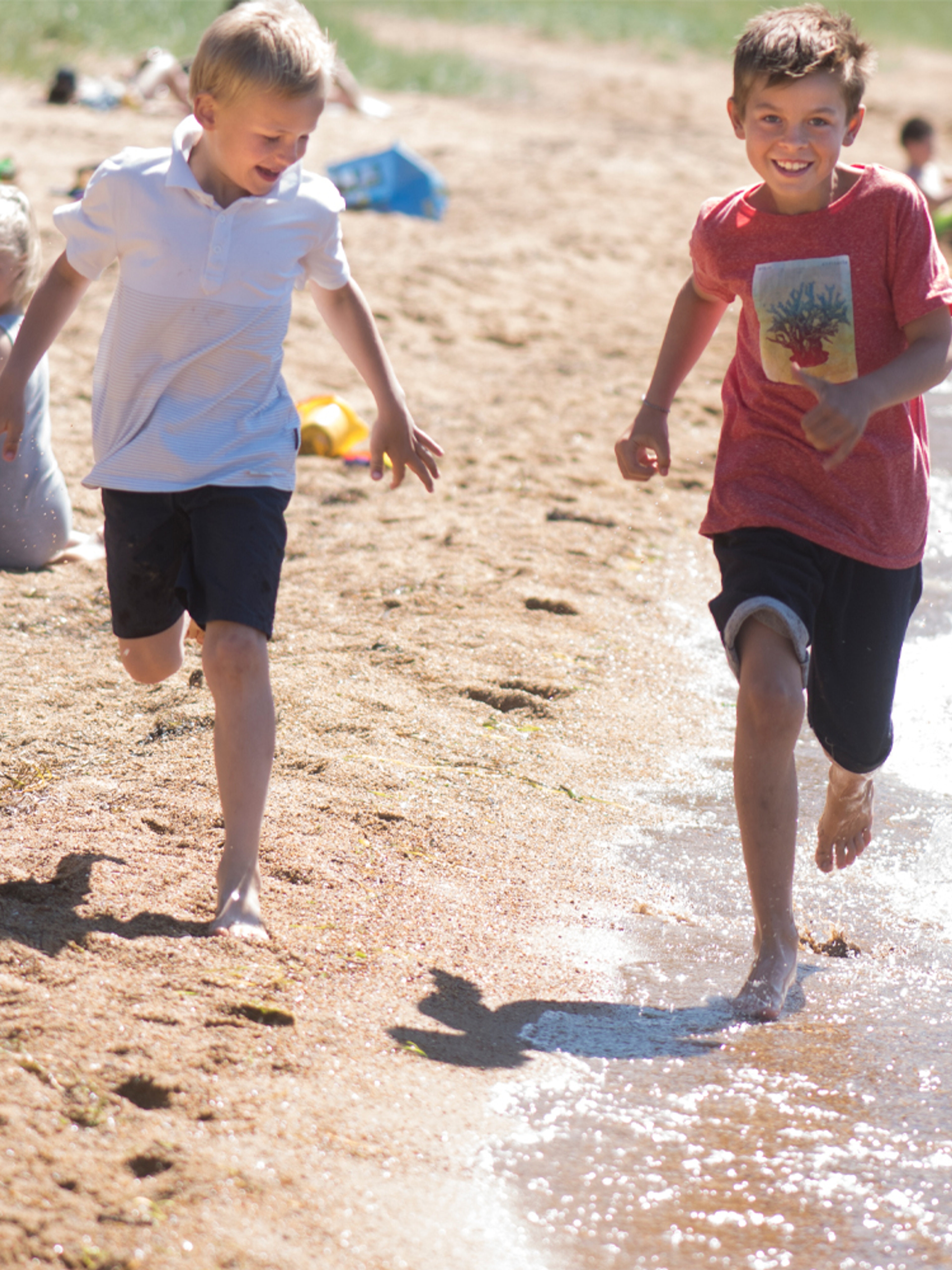 Two children running by the waterline on Kvavik beach in Lyngdal, Southern Norway