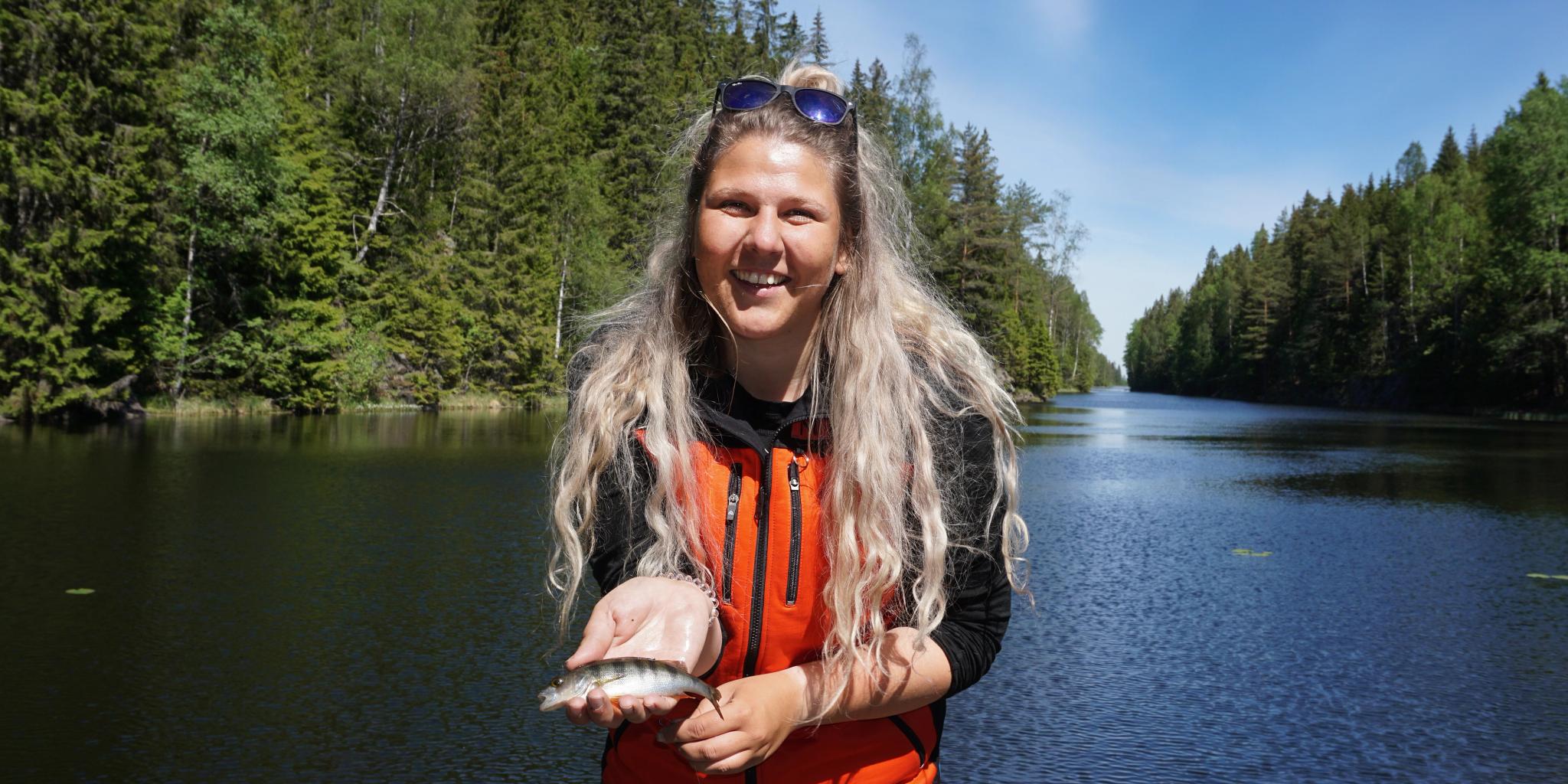 A woman holding a small fish in the fishing paradise Norway