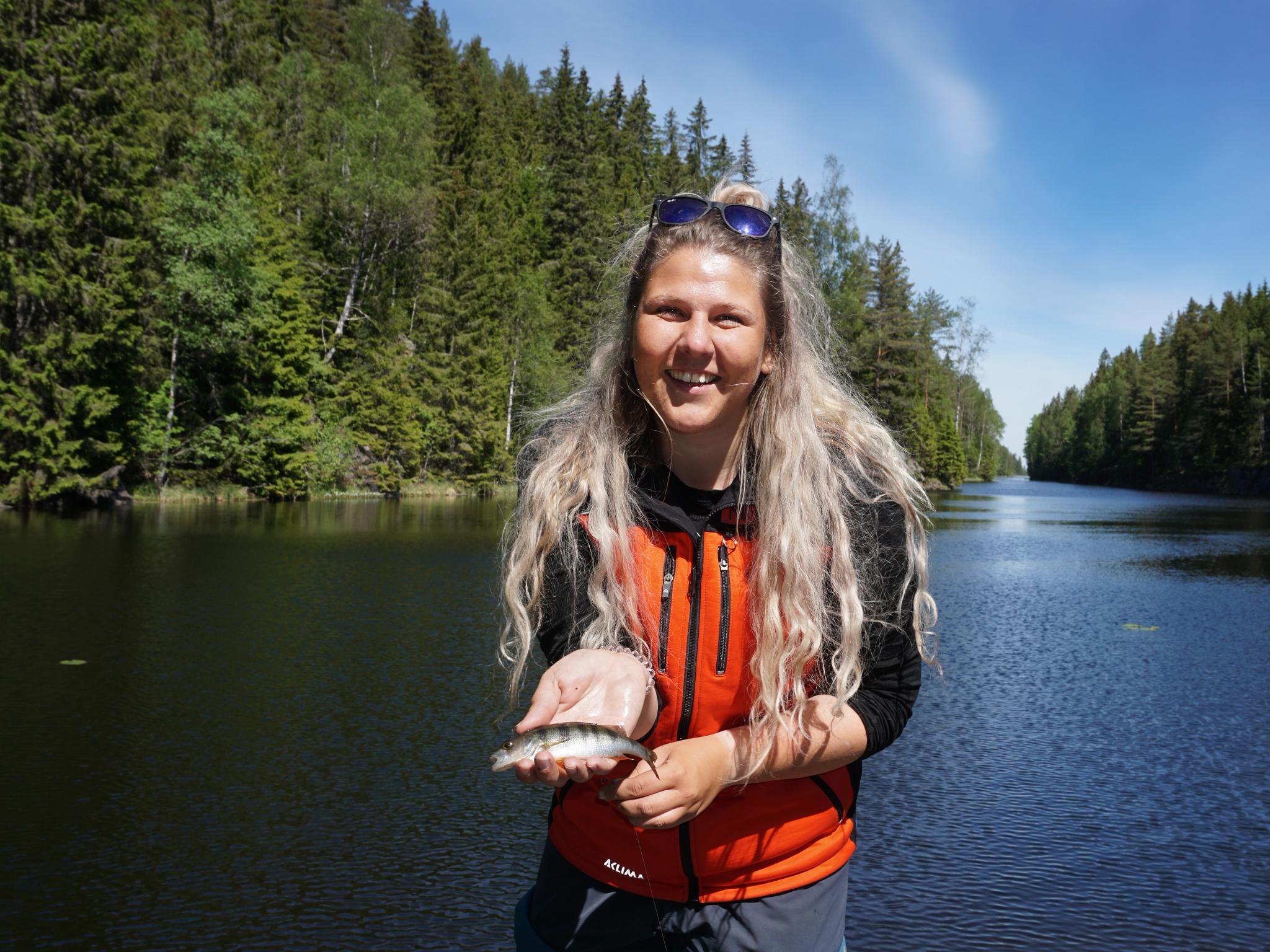 A woman holding a small fish in the fishing paradise Norway