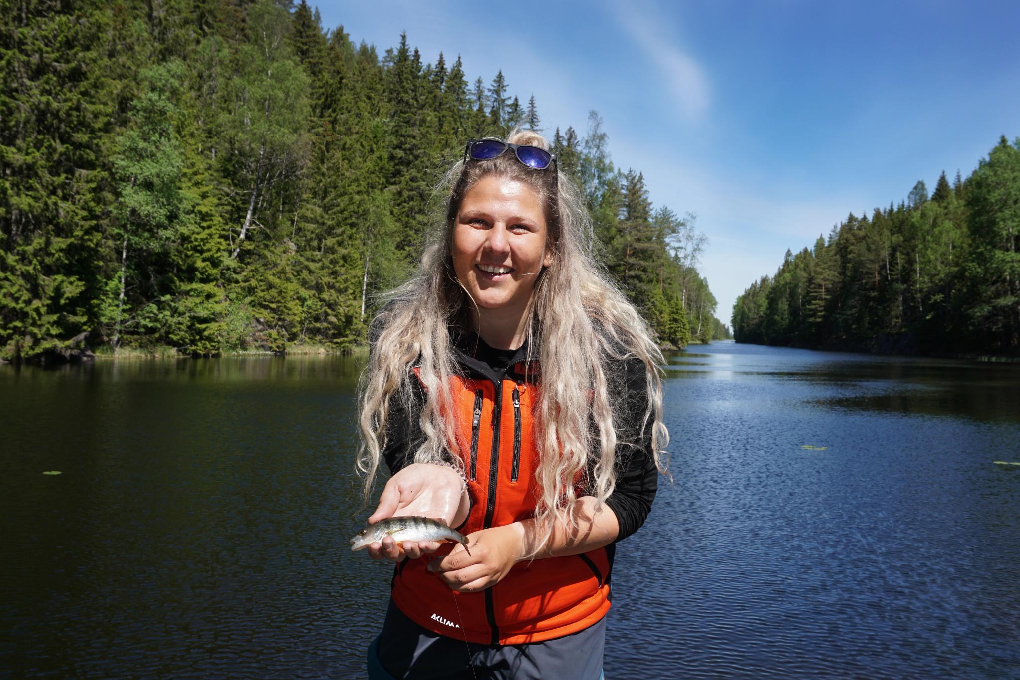 Eine Frau, die einen kleinen Fisch im Anglerparadies Norwegen hält.