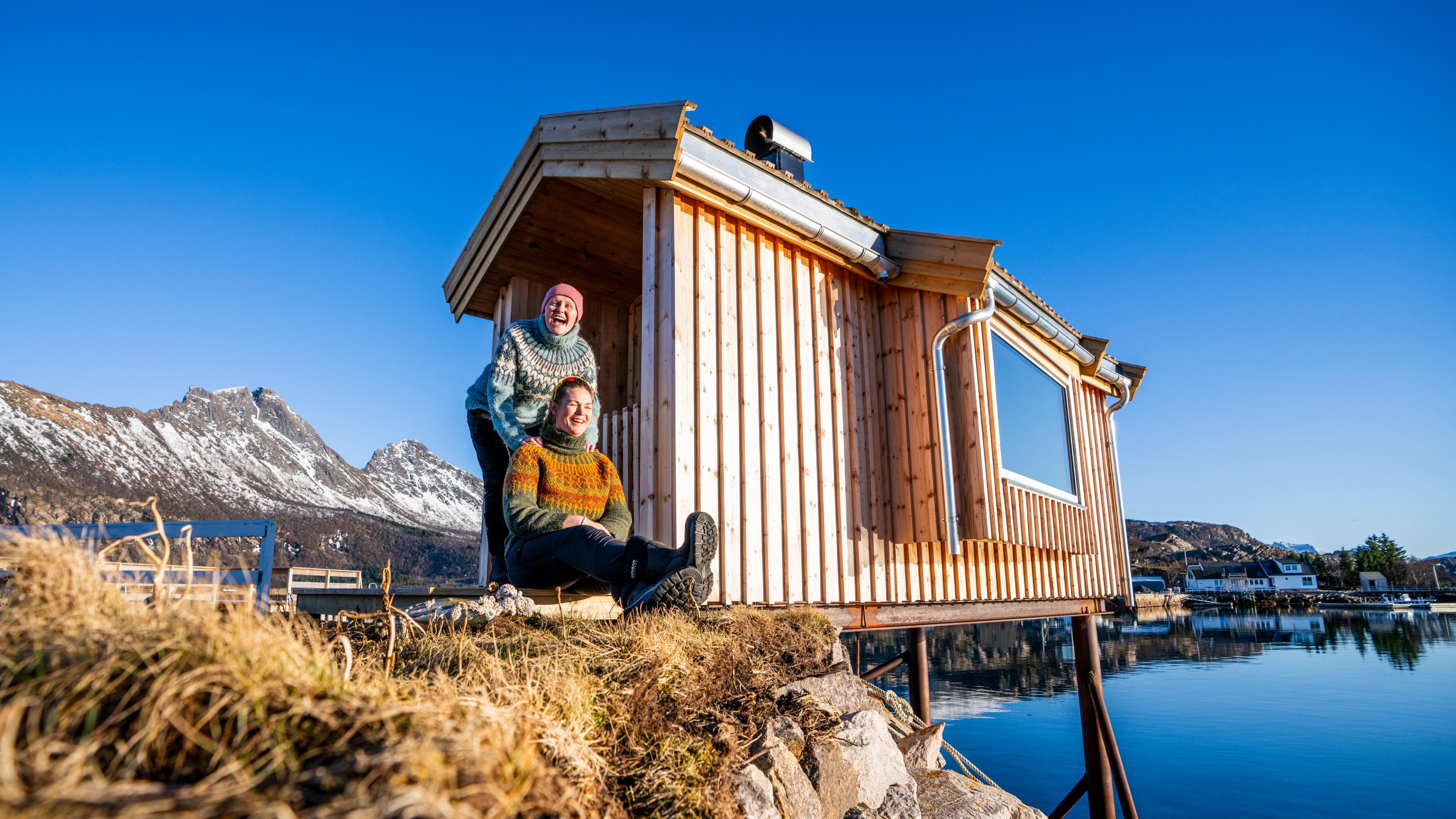 Two women in front of a sauna house by the sea