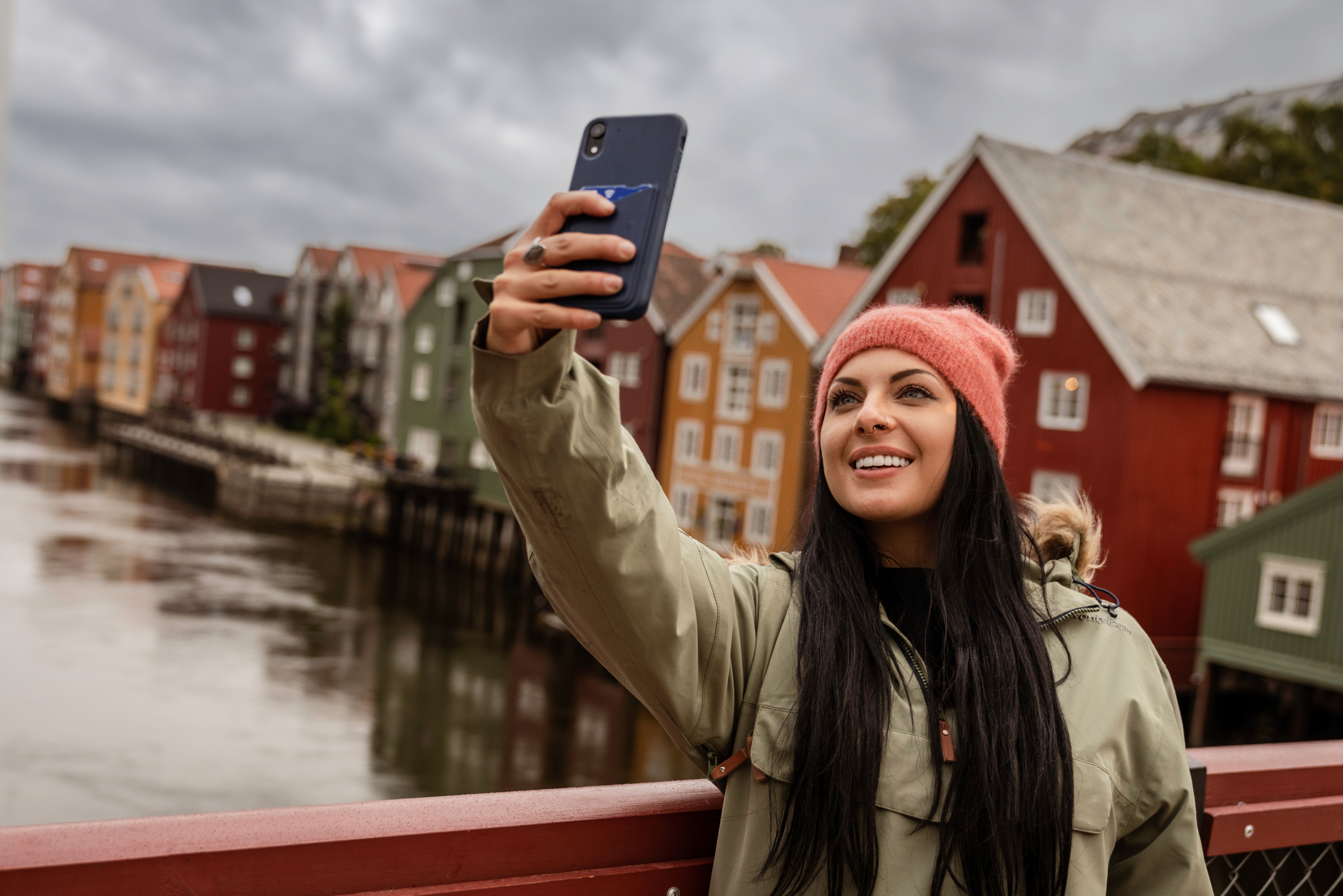 A woman standing taking a selfie on Gamle Bybro in Trondheim