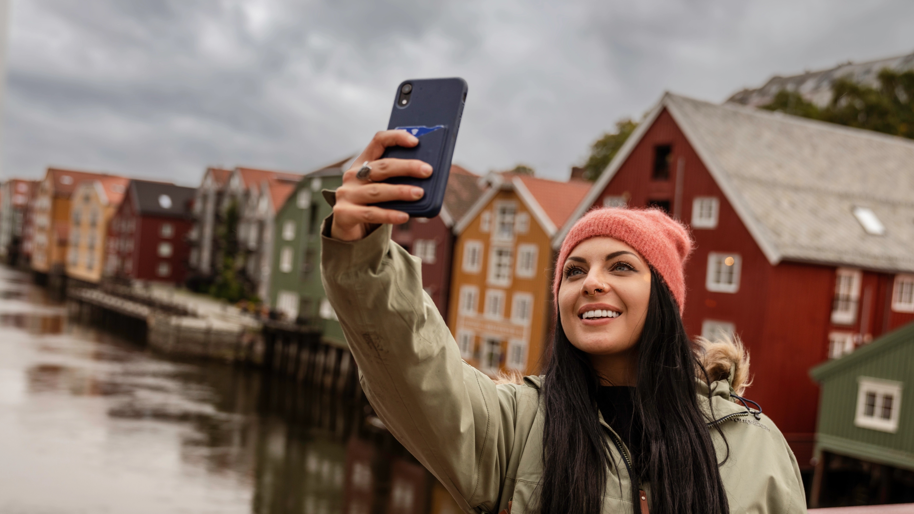 A woman standing taking a selfie on Gamle Bybro in Trondheim