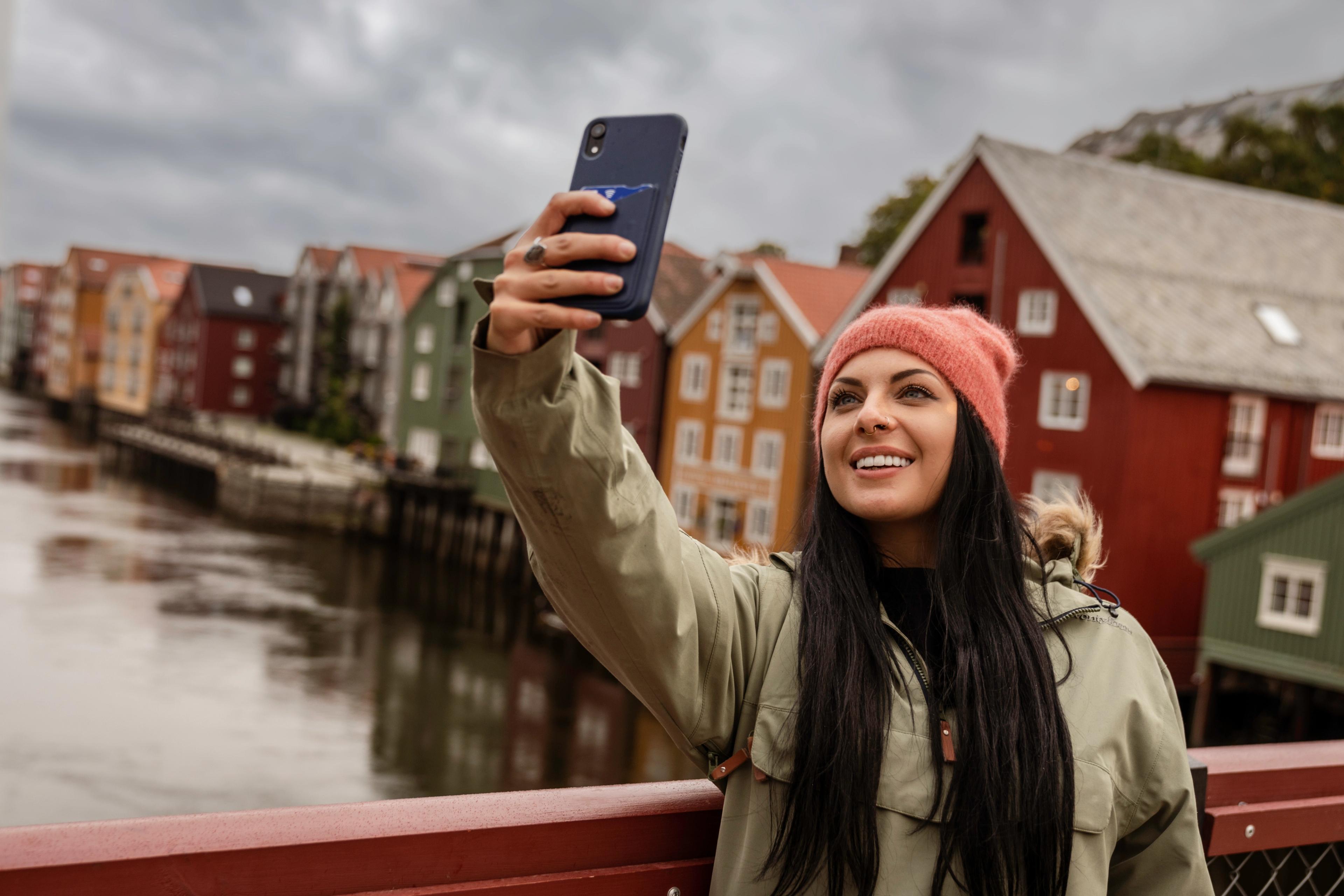 A woman standing taking a selfie on Gamle Bybro in Trondheim