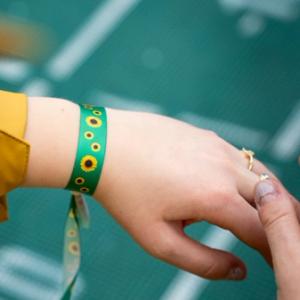 Hånd med Solsikkemerket-bånd på