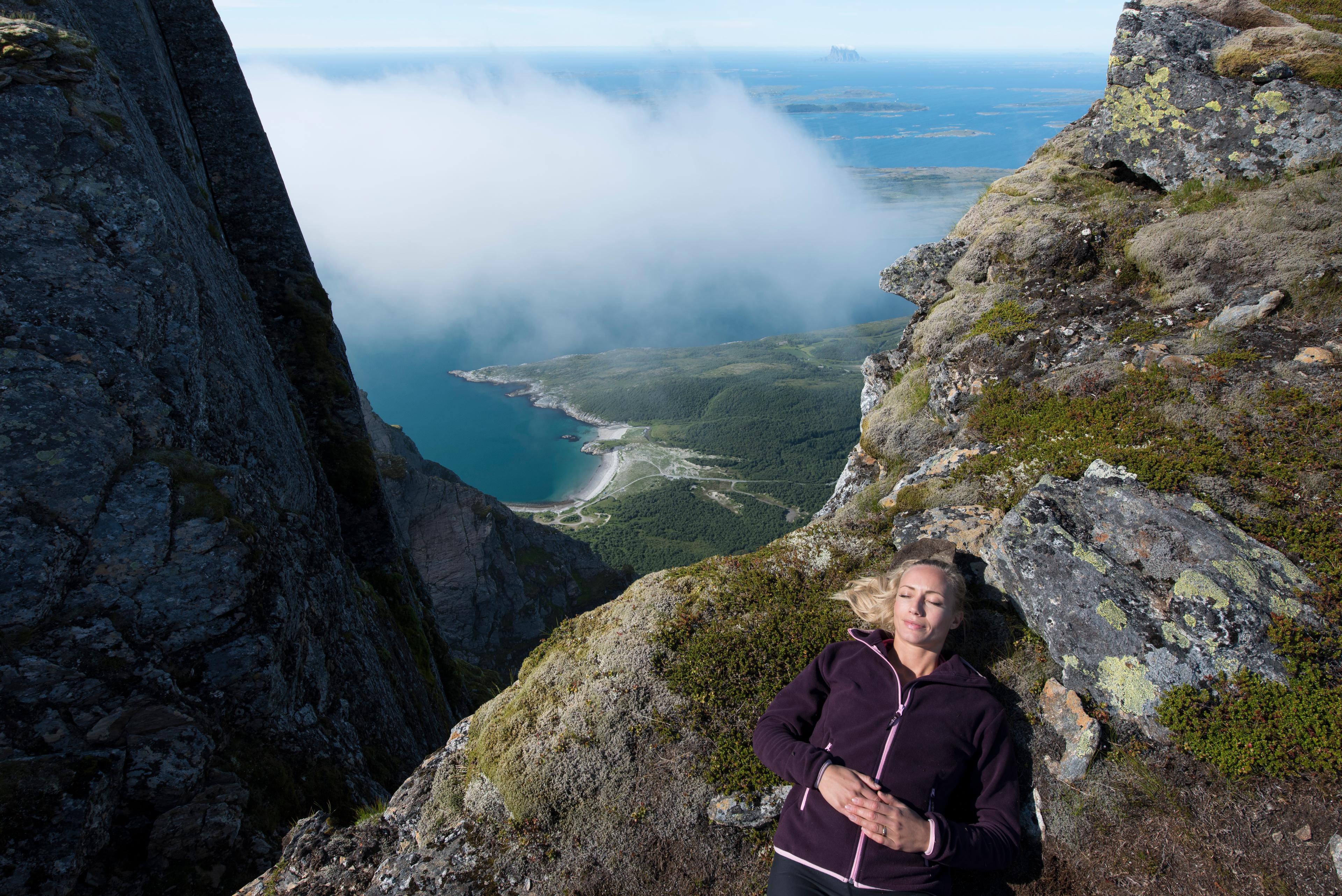 Una mujer se toma un descanso durante una jornada de senderismo por la montañas de Dønnamannen, en Helgeland, Norte de Noruega, con el océano de fondo.