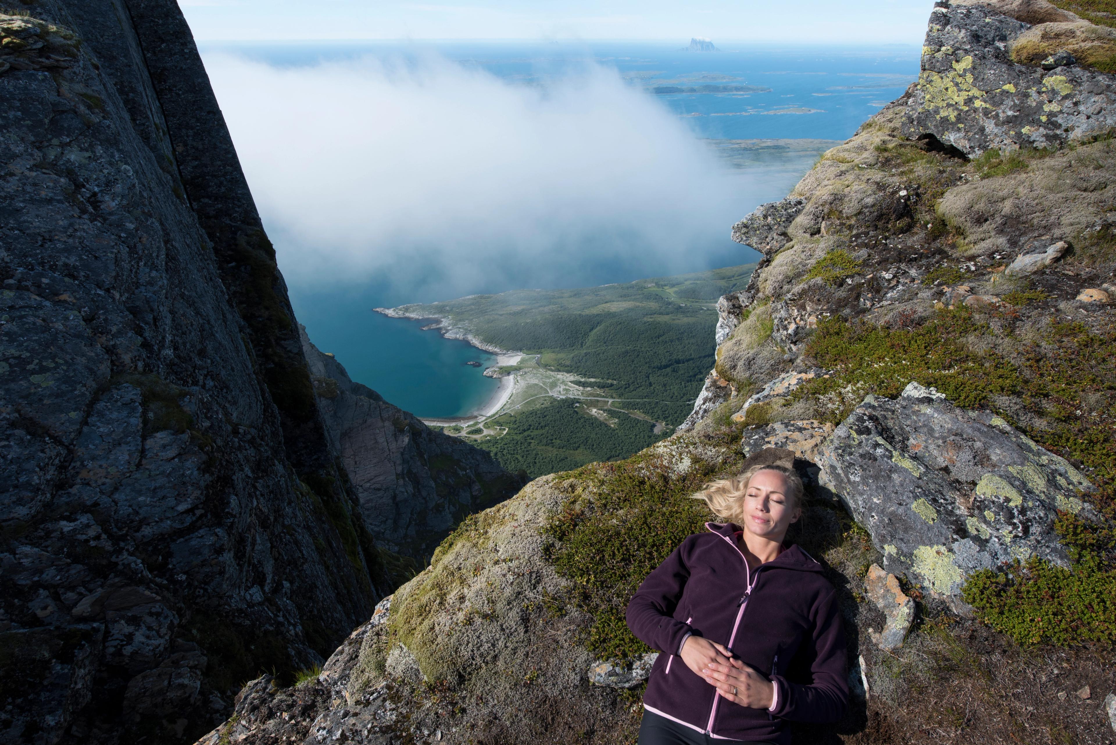 Una mujer se toma un descanso durante una jornada de senderismo por la montañas de Dønnamannen, en Helgeland, Norte de Noruega, con el océano de fondo.