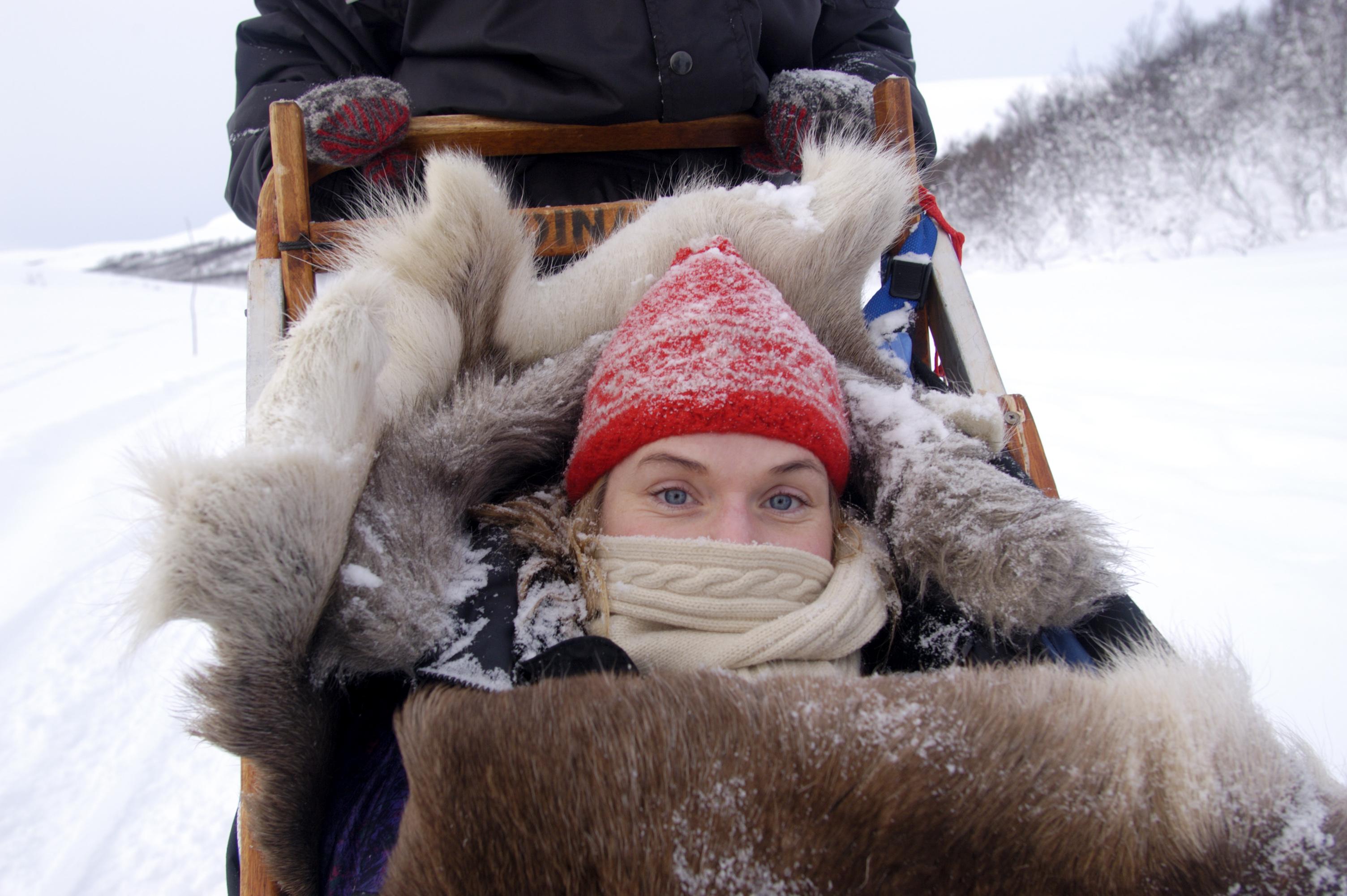 A girl snuggling up in a dog sled in Northern Norway