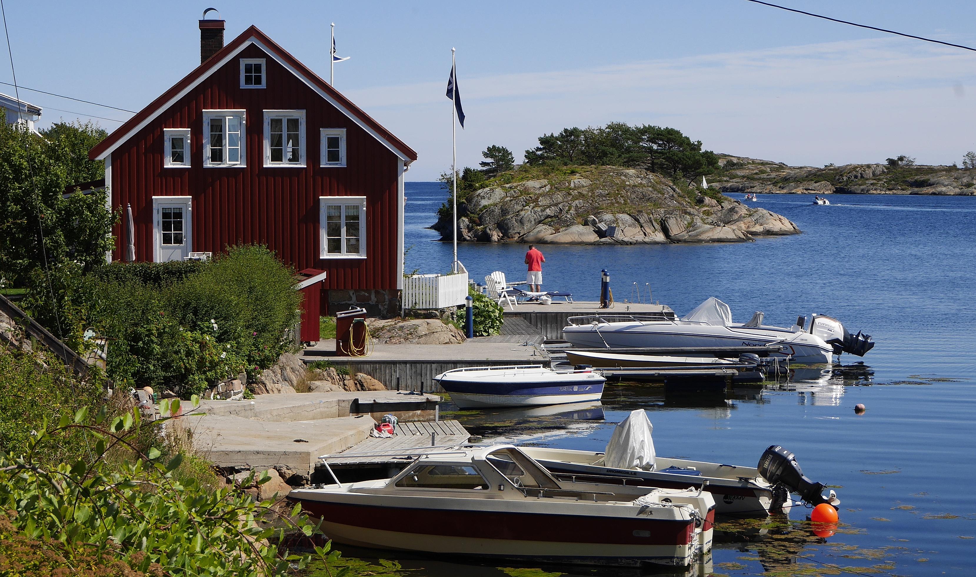 View of a house near the water and a few boats in Sandøya outside of Tvedestrand, Southern Norway