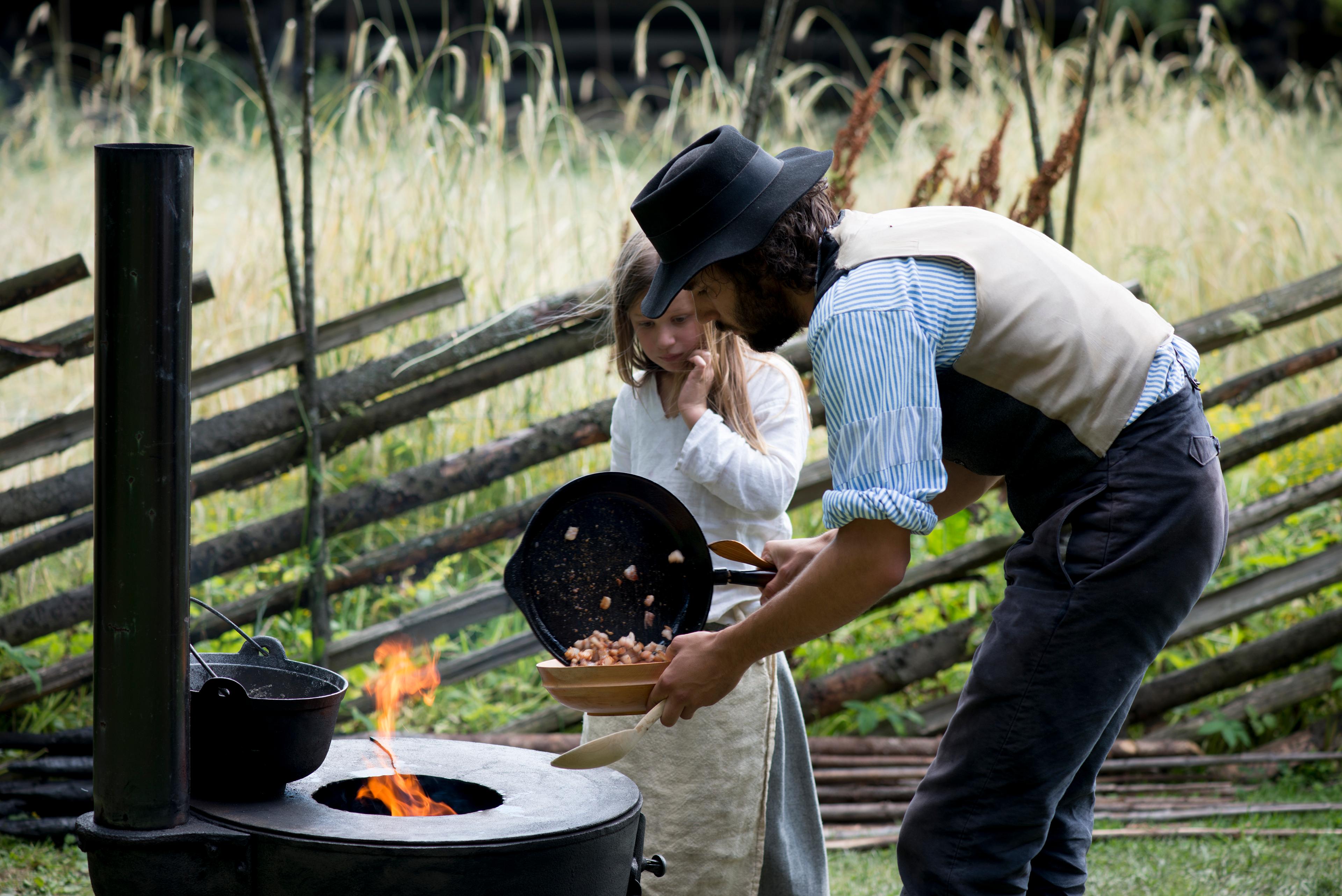 Father and daughter cooking outside