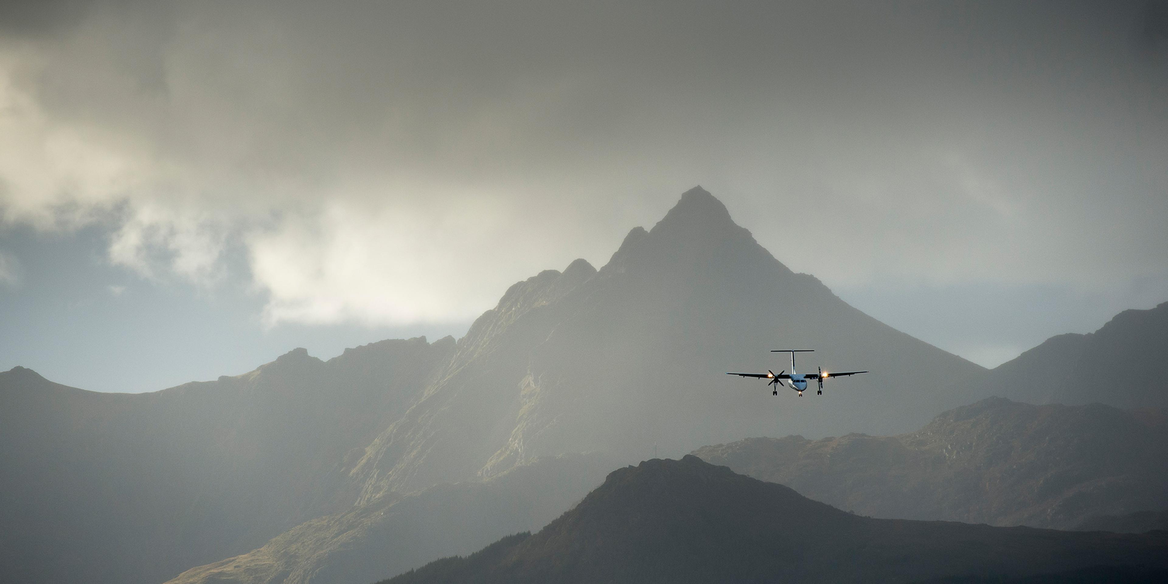 A plane flying over steep mountains in Lofoten