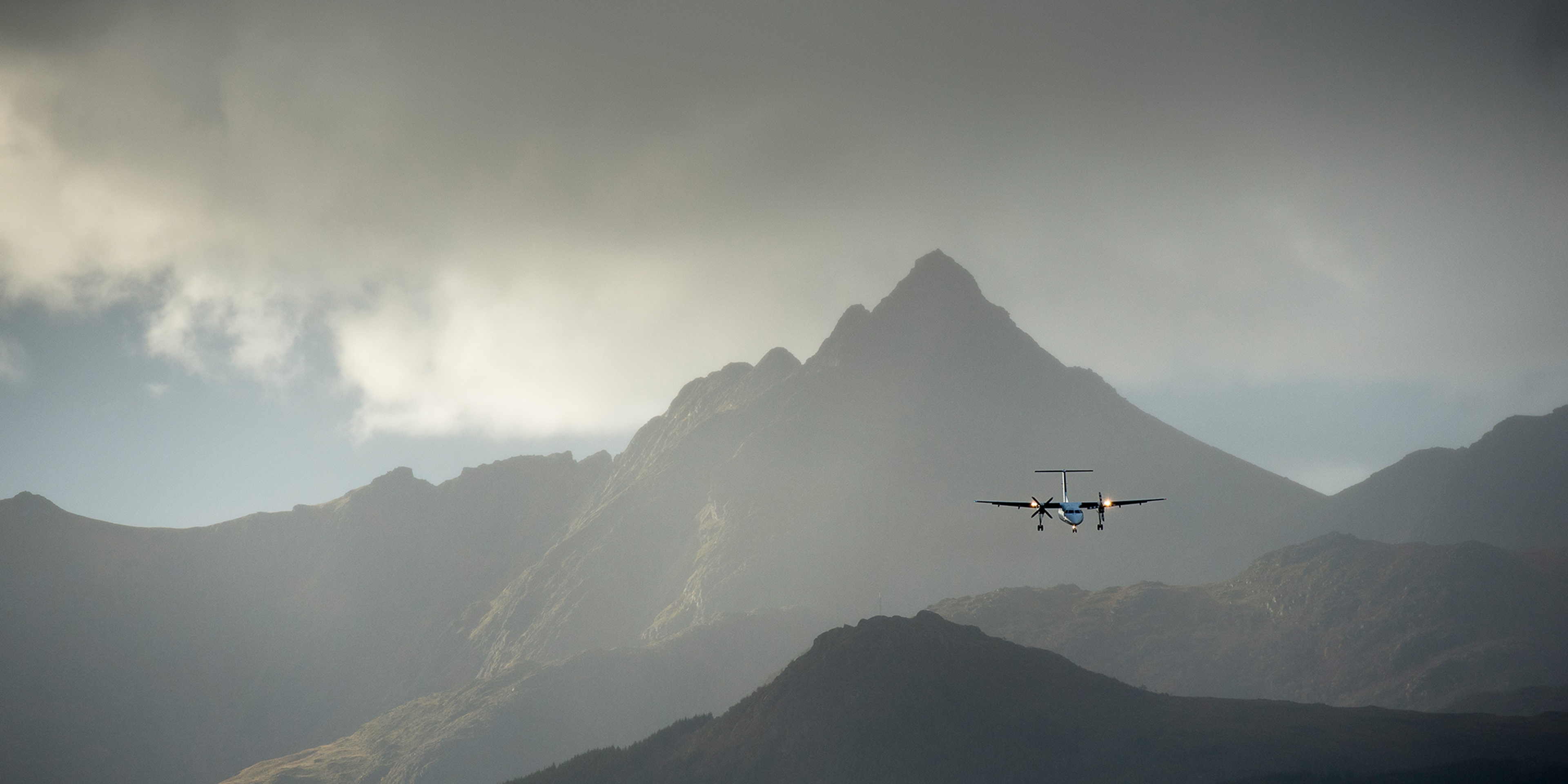 A plane flying over steep mountains in Lofoten
