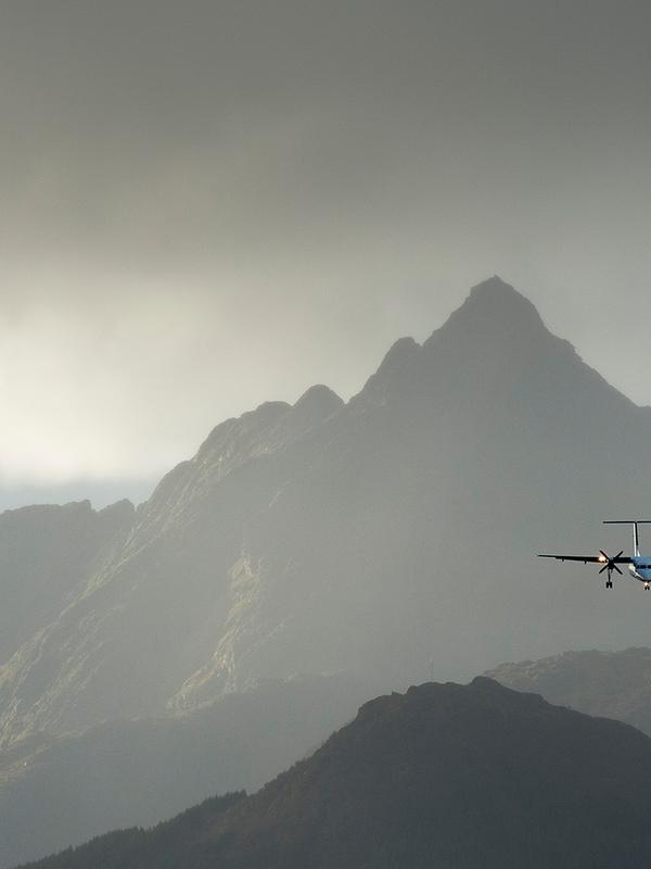 A plane flying over steep mountains in Lofoten