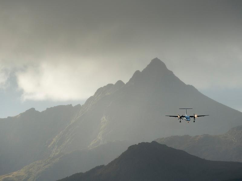 A plane flying over steep mountains in Lofoten