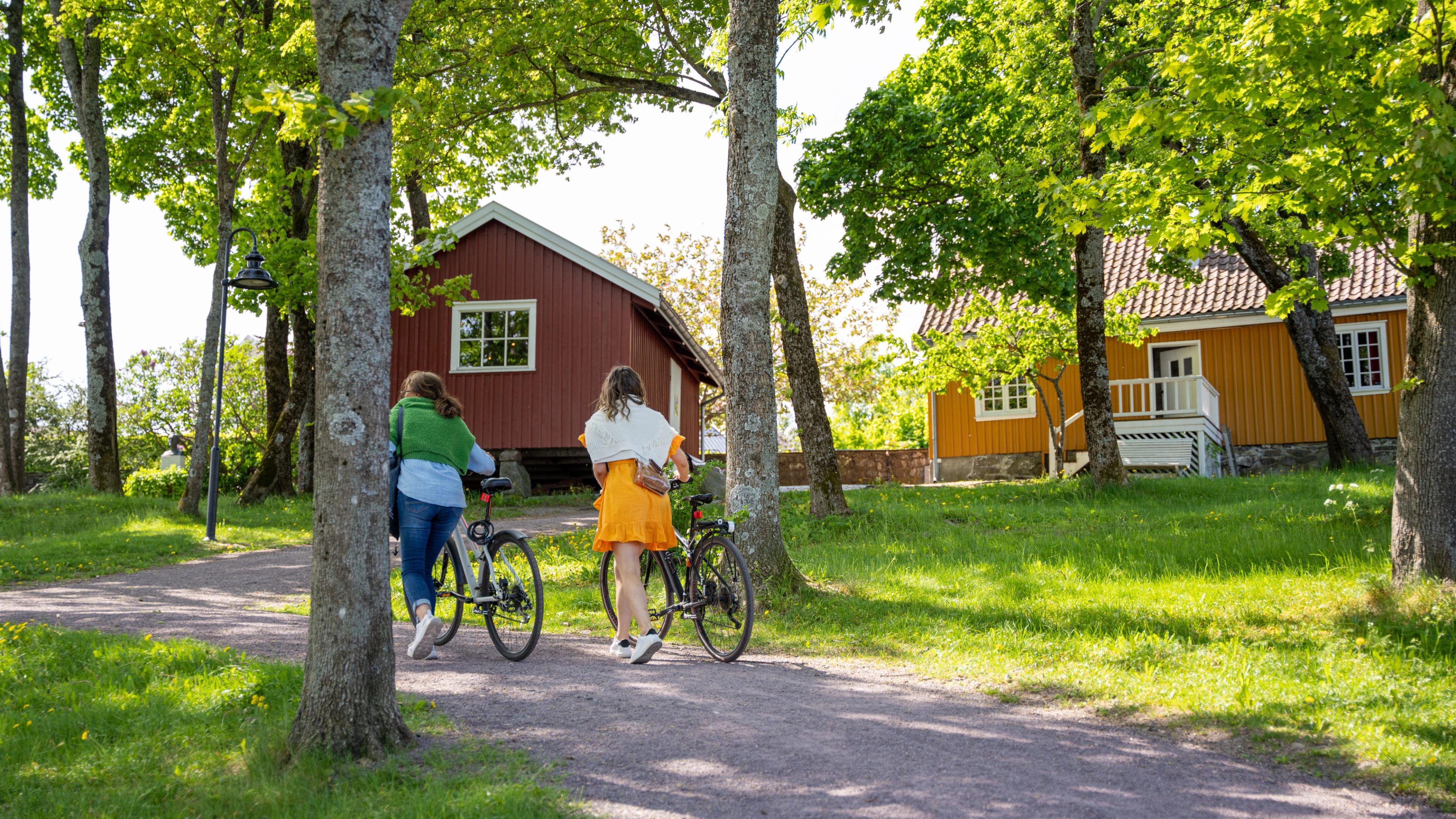 Two women walking with bike in front of Edvard Munch's old house in Åsgårdstrand