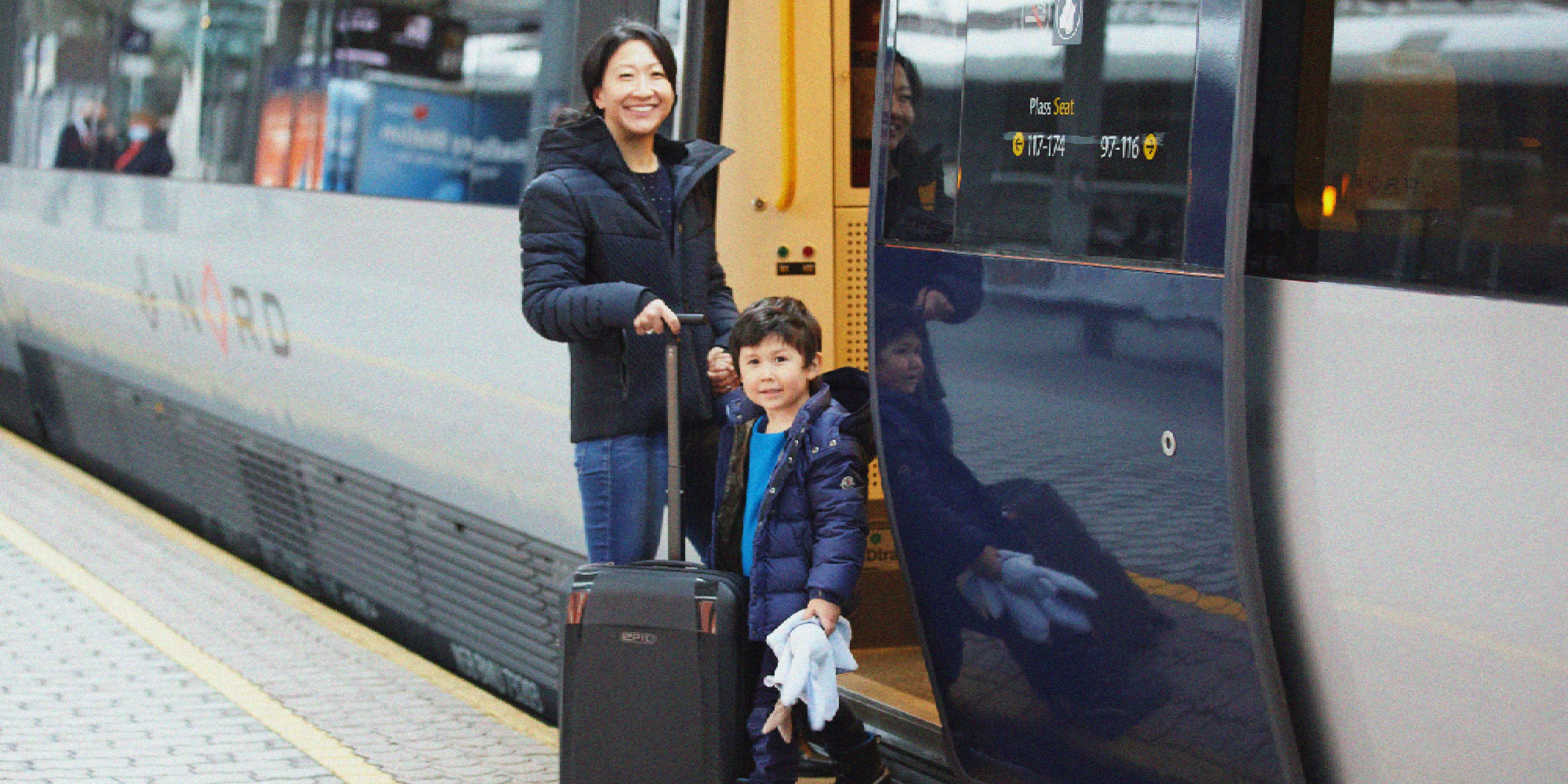A women and a child is standing outside of a train.