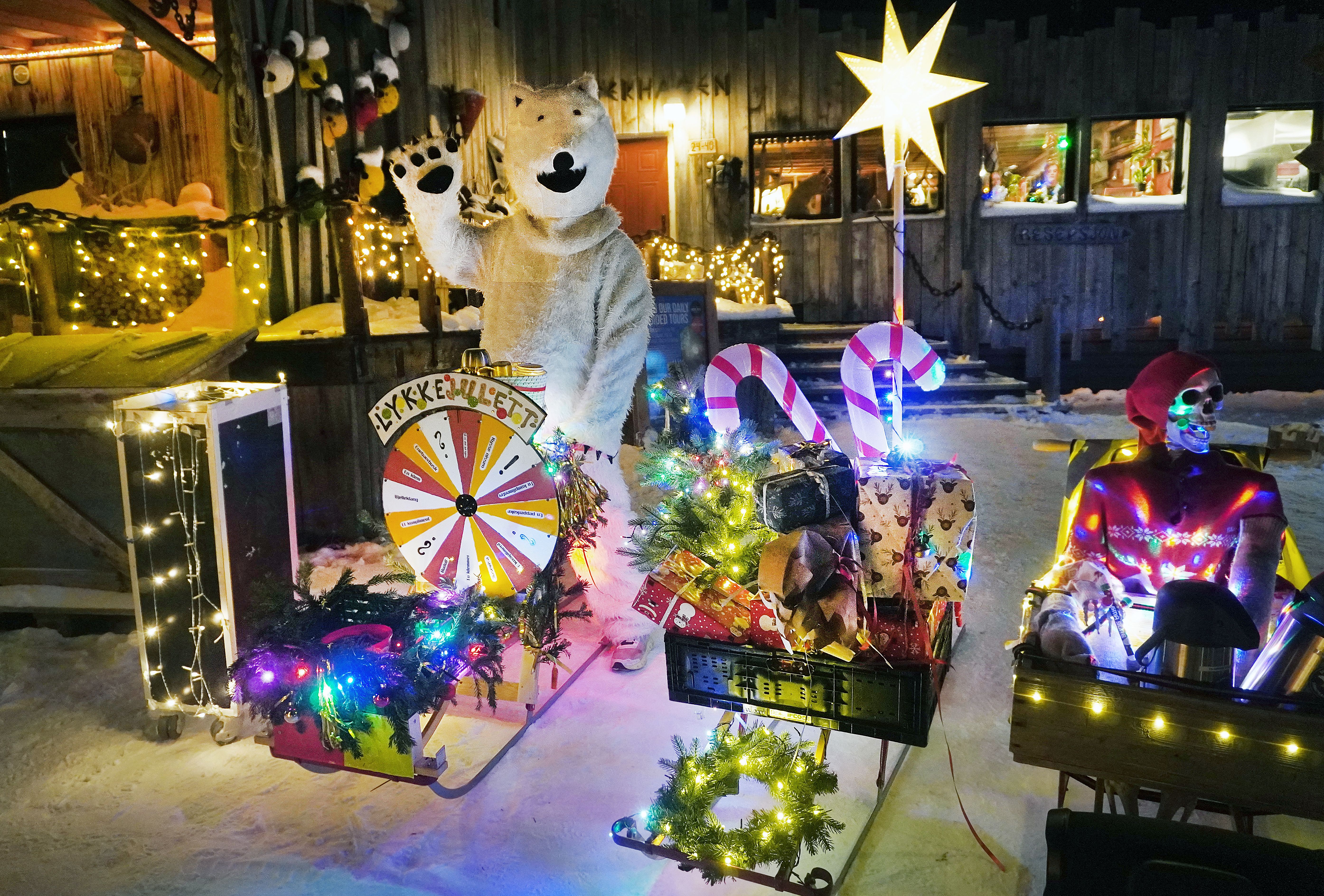 A man dressed like ice bear by Christmas decorated kick sleds