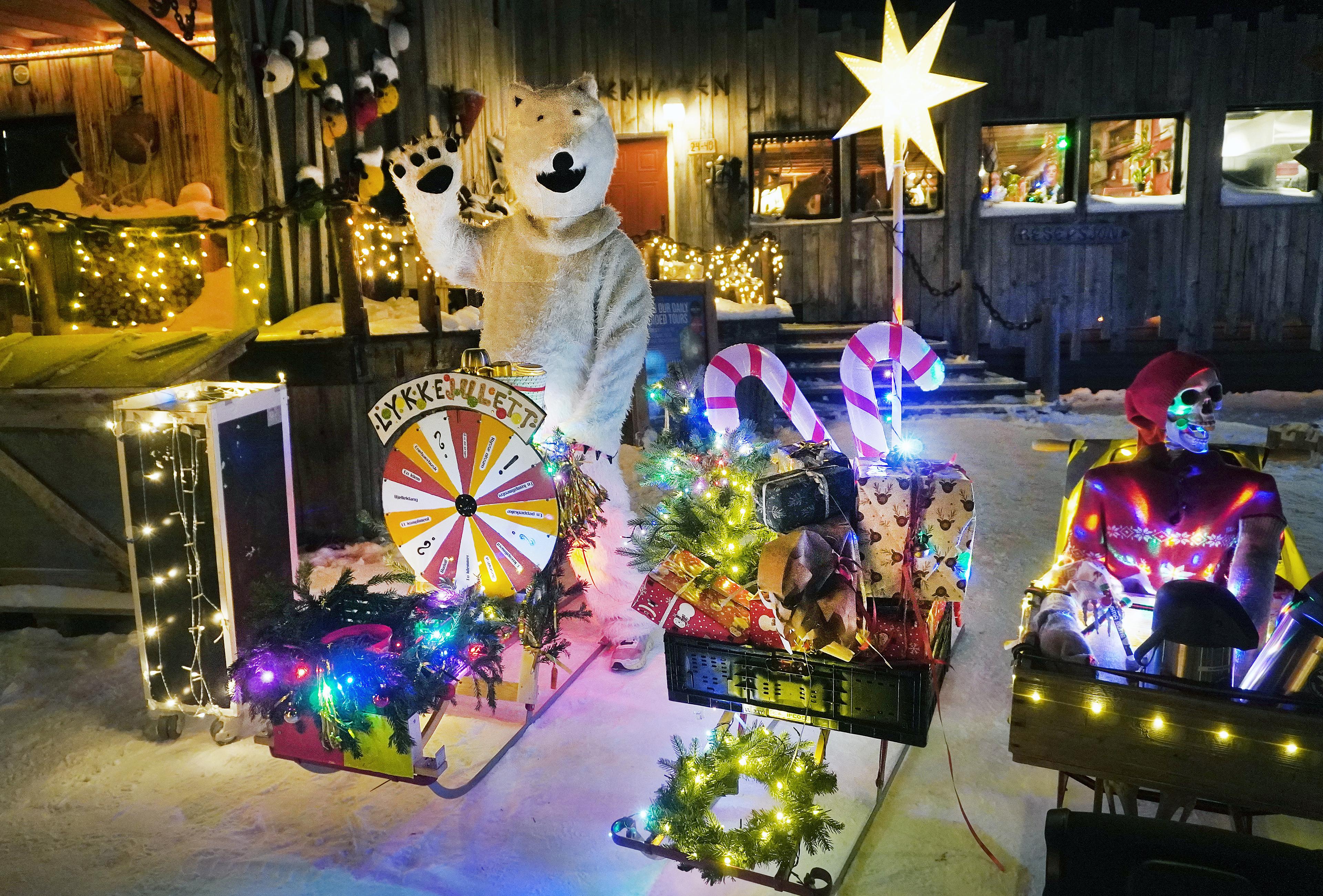 A man dressed like ice bear by Christmas decorated kick sleds