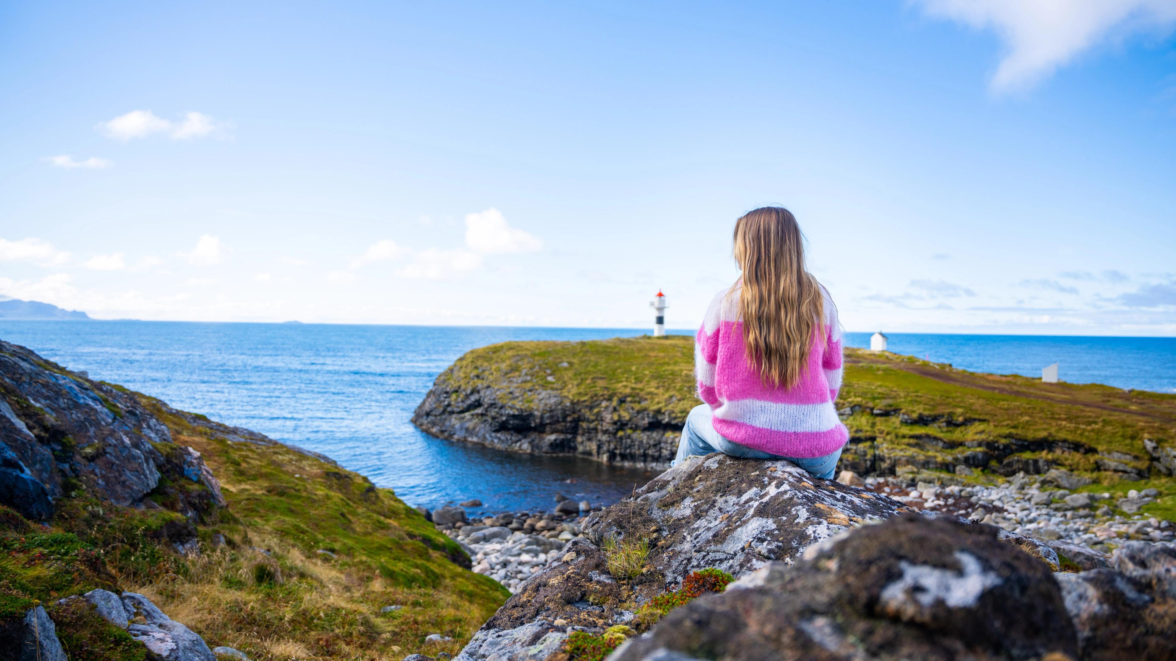 A woman looking at the view of Børhella lighthouse at Andøya, Northern Norway