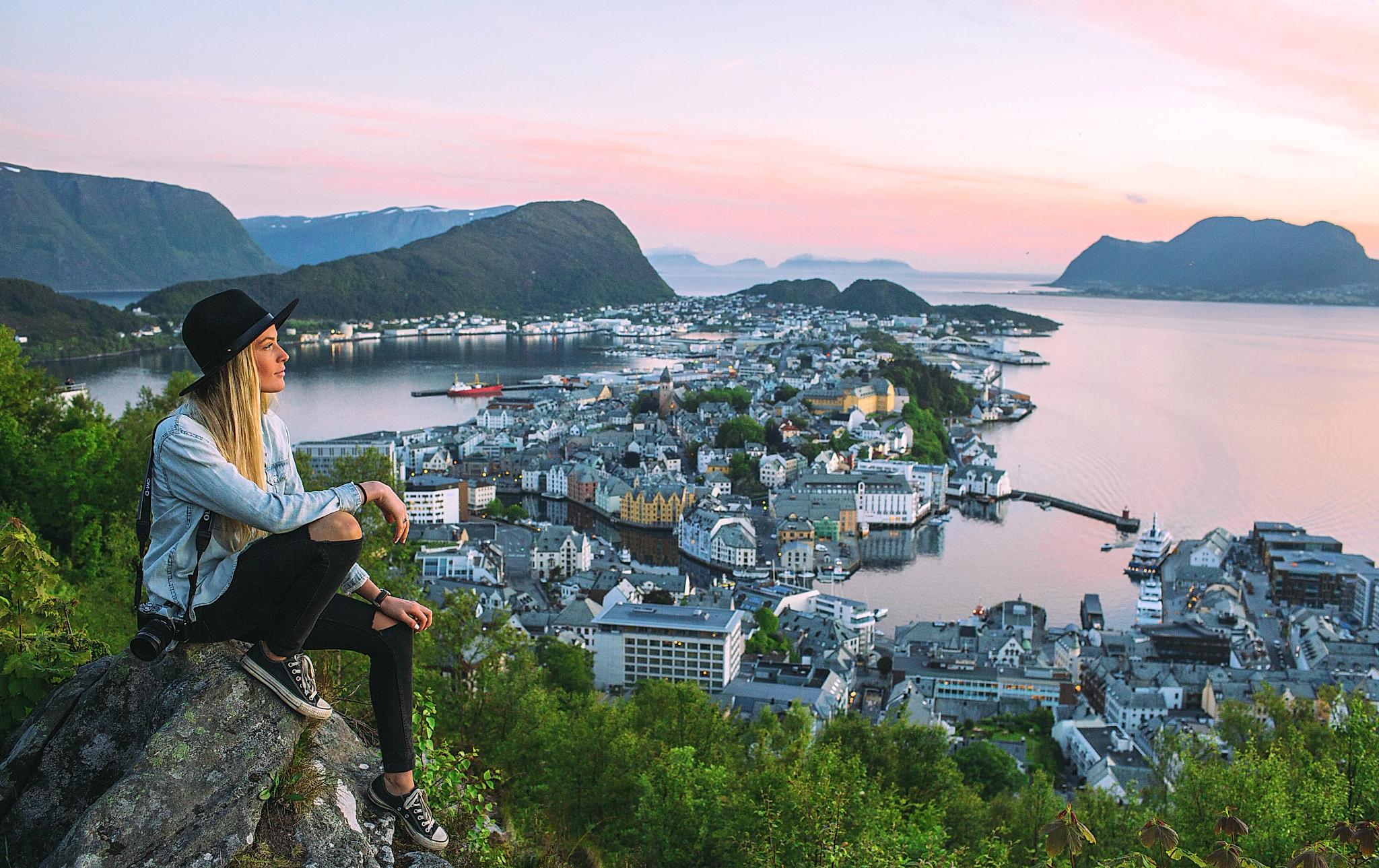 Kvinne på toppen av Aksla ser ut over Ålesund by