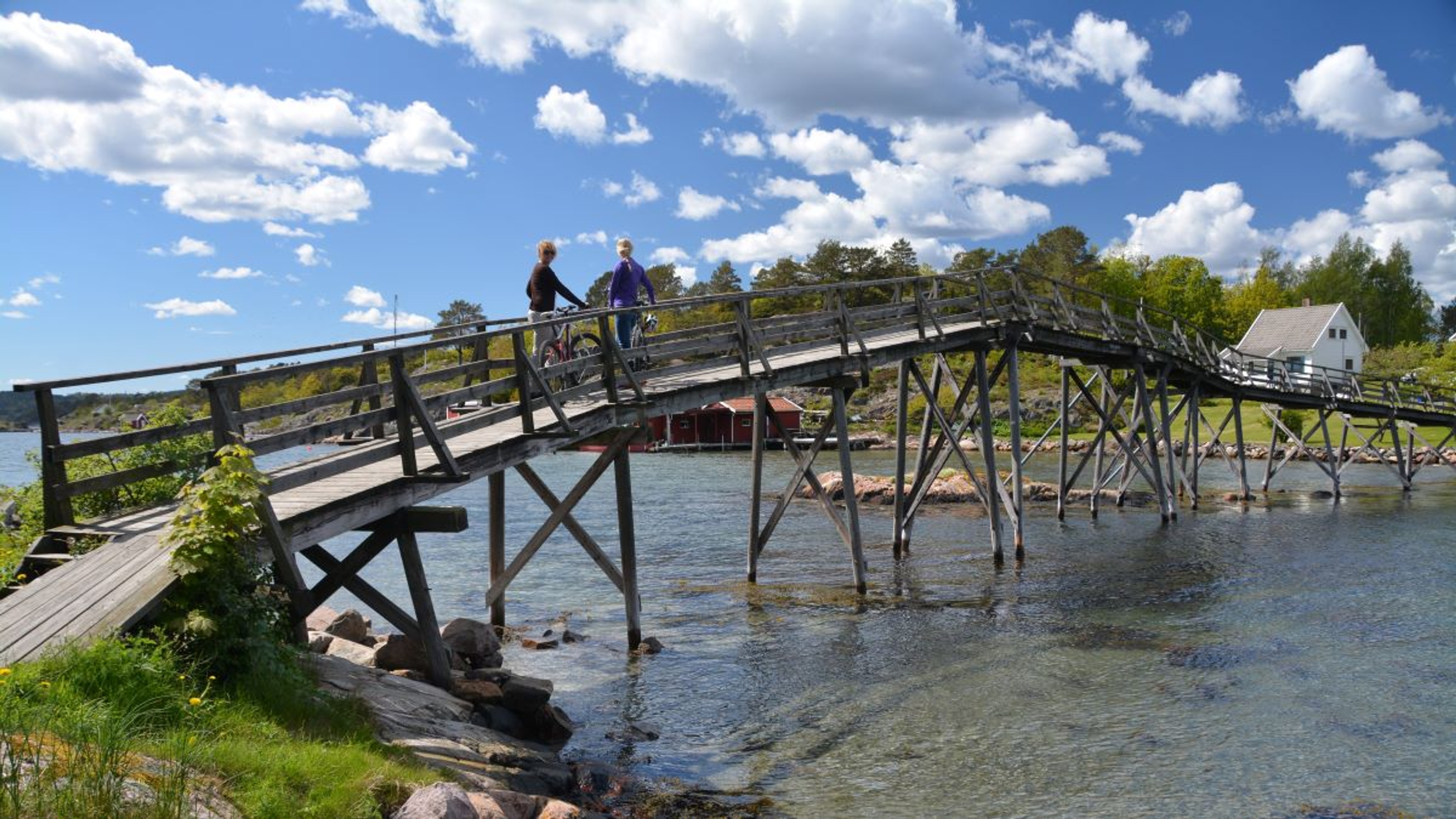 Two persons standing on a bridge with bicycles in Grimstad, Southern Norway.